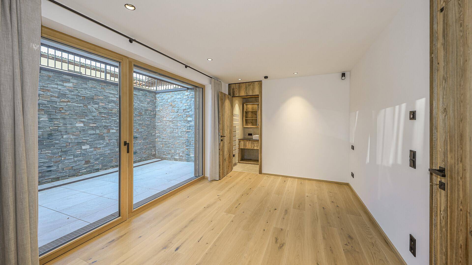 Helles Zimmer mit Holzboden und großen Schiebetüren zu einem Innenhof.