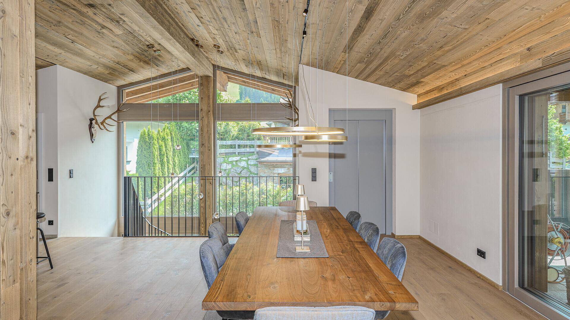 Heller Essbereich mit großem Holztisch, modernen Stühlen und Zugang zum Balkon.