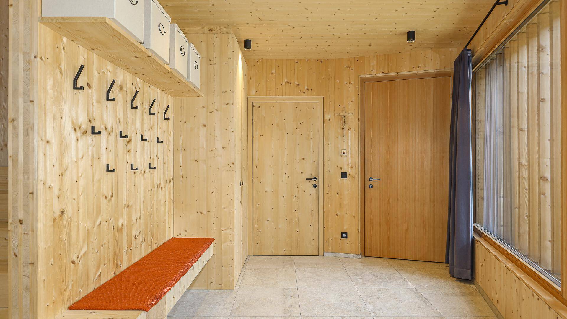 Funktionaler Eingangsbereich mit Garderobe, Holzwänden und Fliesenboden.