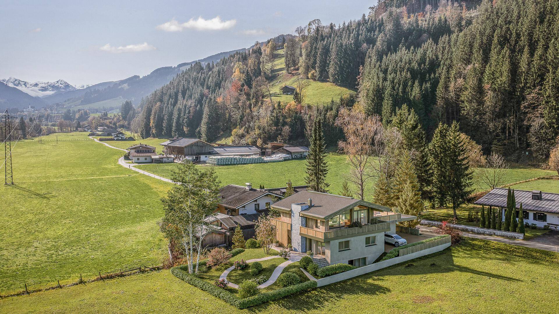 Modernes Wohnhaus in alpiner Umgebung mit gepflegtem Garten und weitem Blick auf die Berglandschaft.