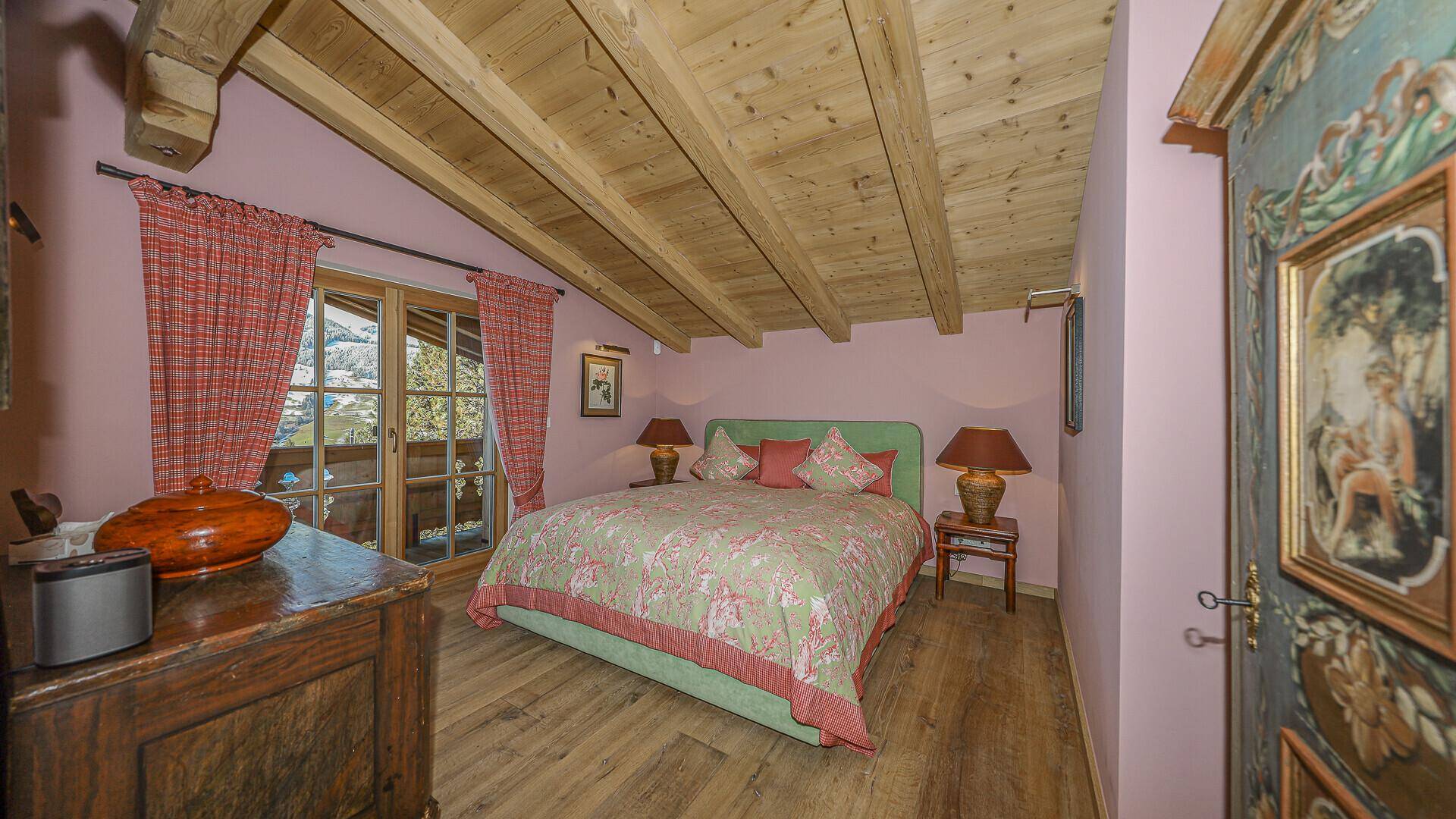 Charmantes Schlafzimmer mit Holzbalkendecke, Balkonzugang und traditioneller Einrichtung im alpinen Stil.