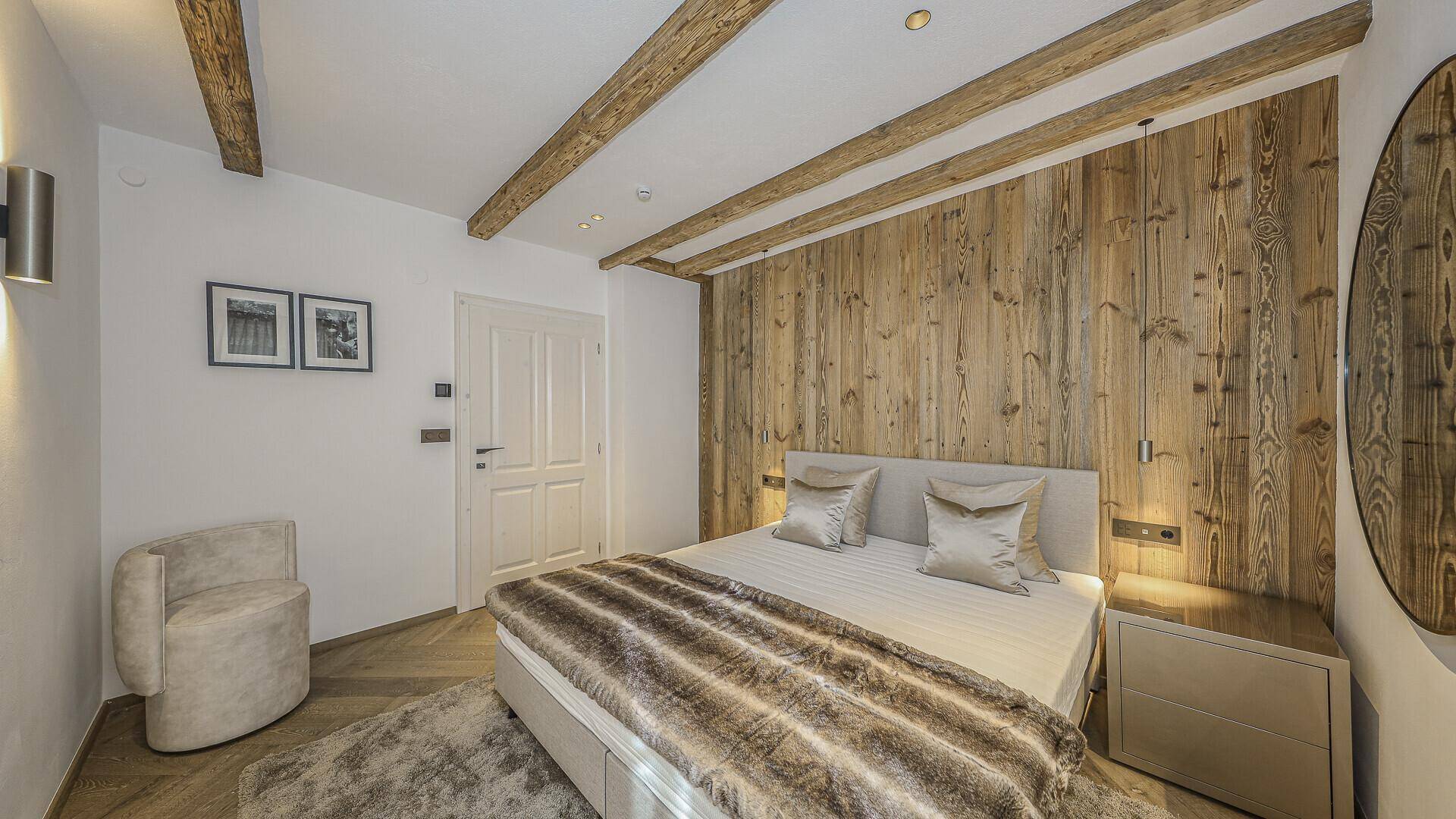 Gemütliches Schlafzimmer mit Holzwand, sichtbaren Balken und modernem Design.