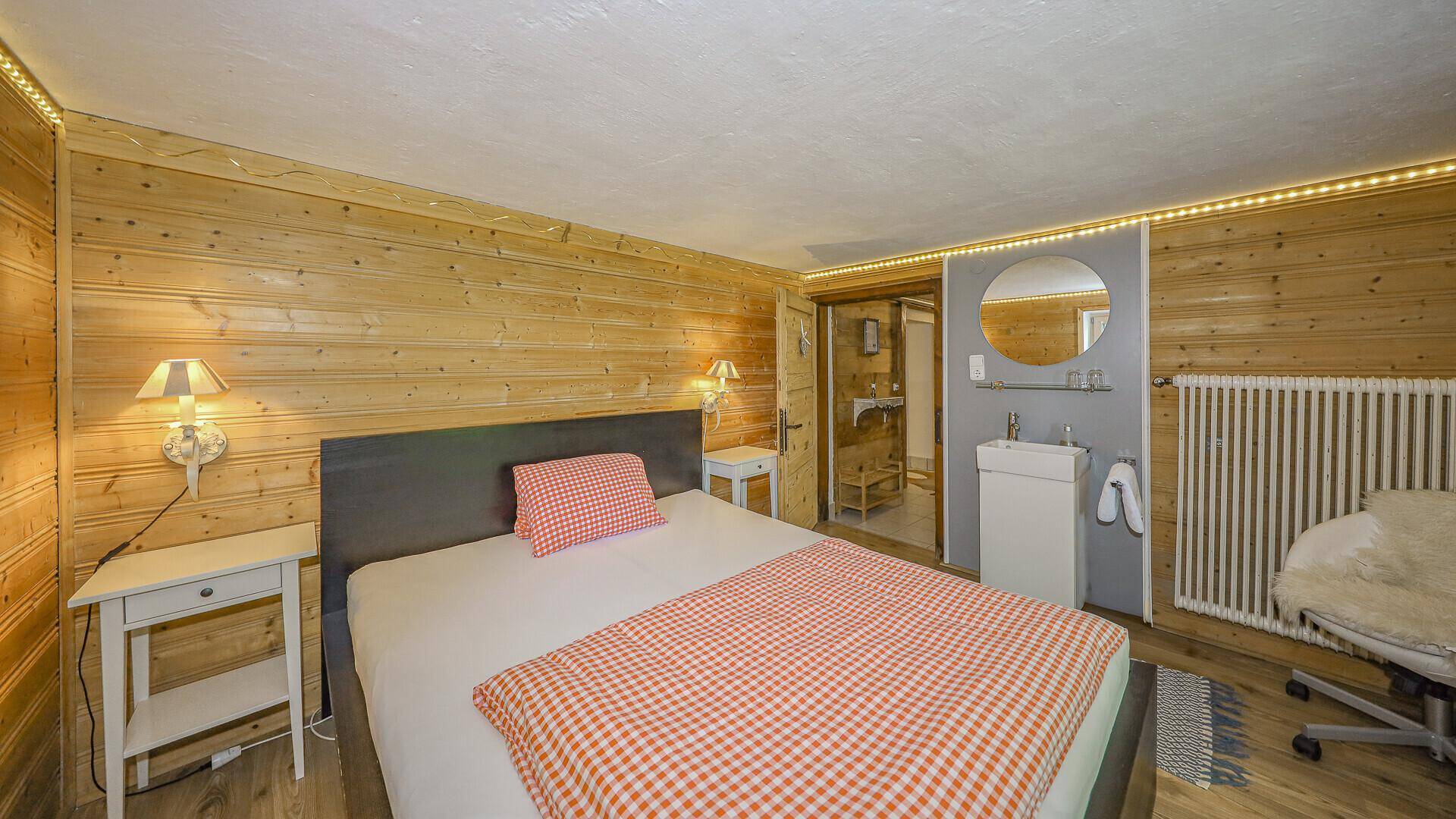 Schlafzimmer mit Holzvertäfelung, integriertem Waschbecken und Spiegel, im traditionellen Stil gehalten.