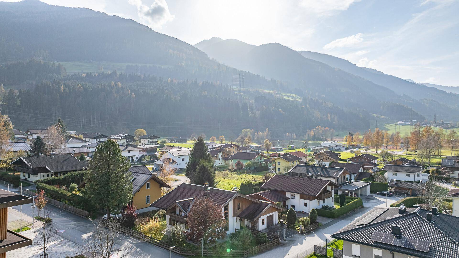 Weitläufiger Blick über die Siedlung mit traditionellen Häusern und majestätischen Bergen.