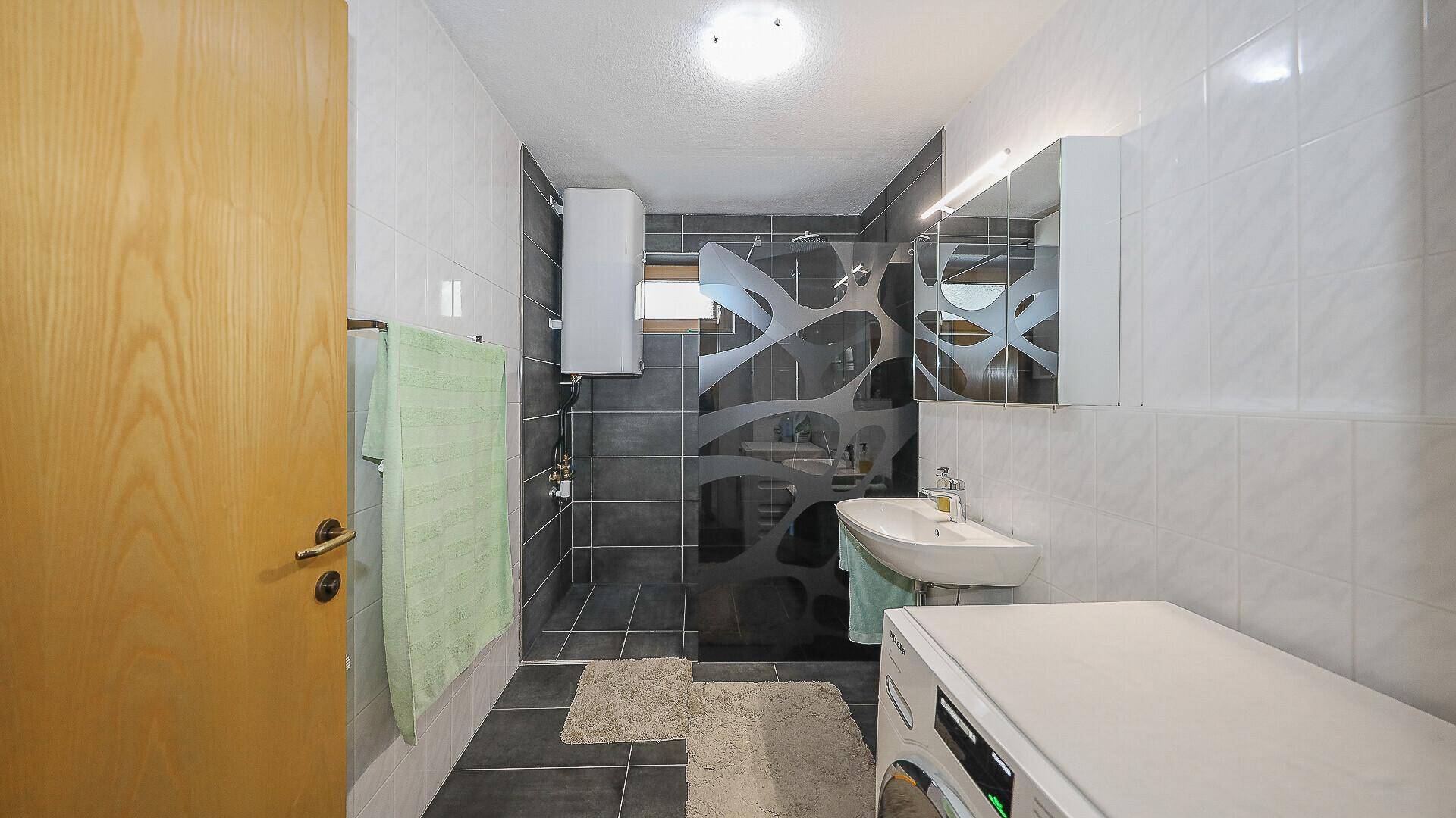 Modernes Badezimmer mit Dusche, Waschbecken und Waschmaschine.