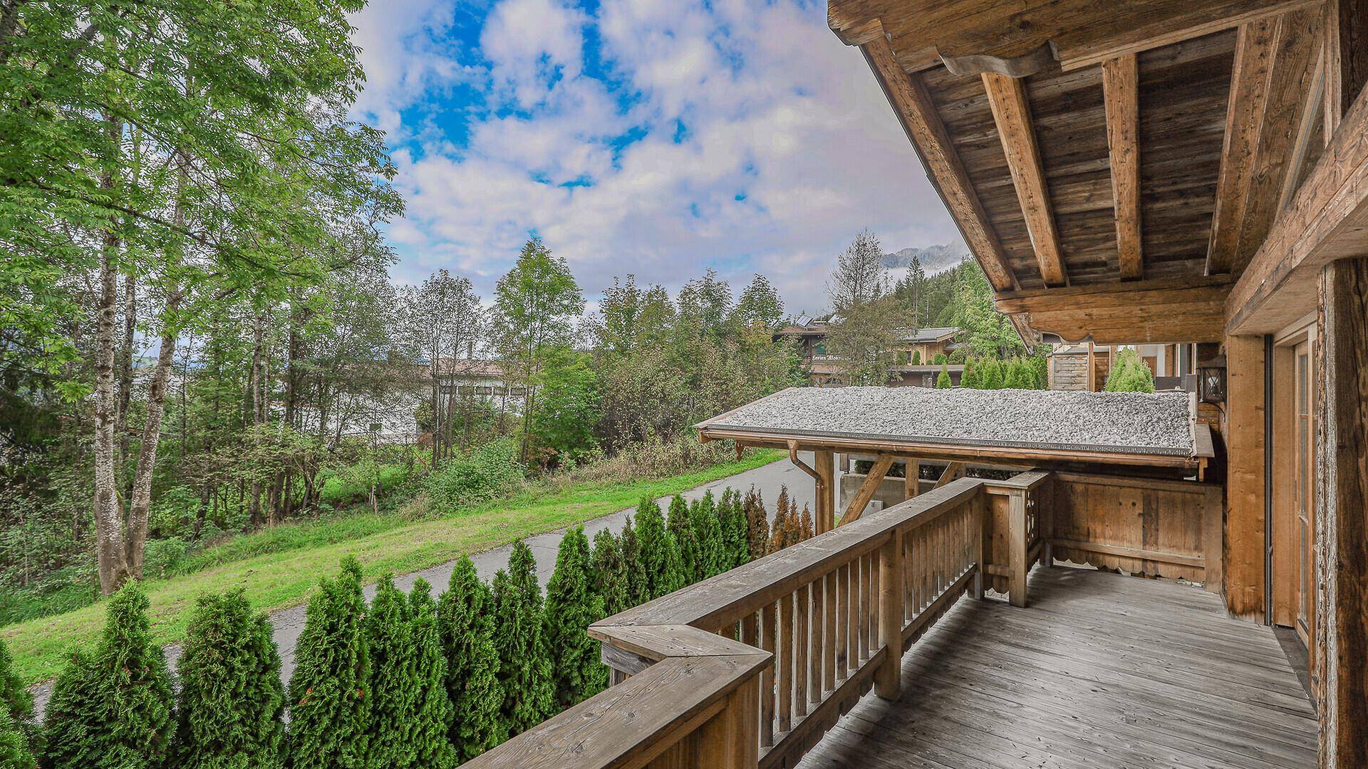 Großer Holzbalkon mit Geländer und weitem Blick ins Grüne und auf die Umgebung.