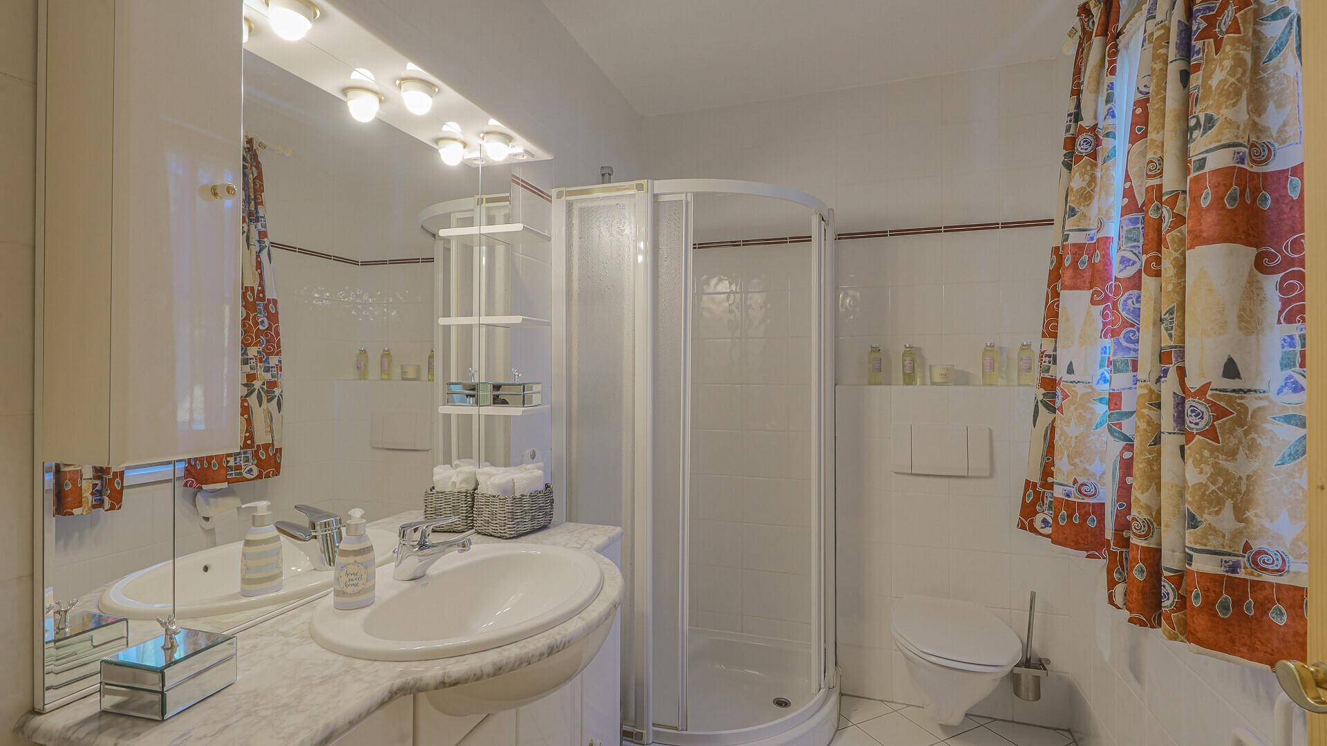 Traditionelles Badezimmer mit Doppelwaschbecken, Duschkabine und WC.