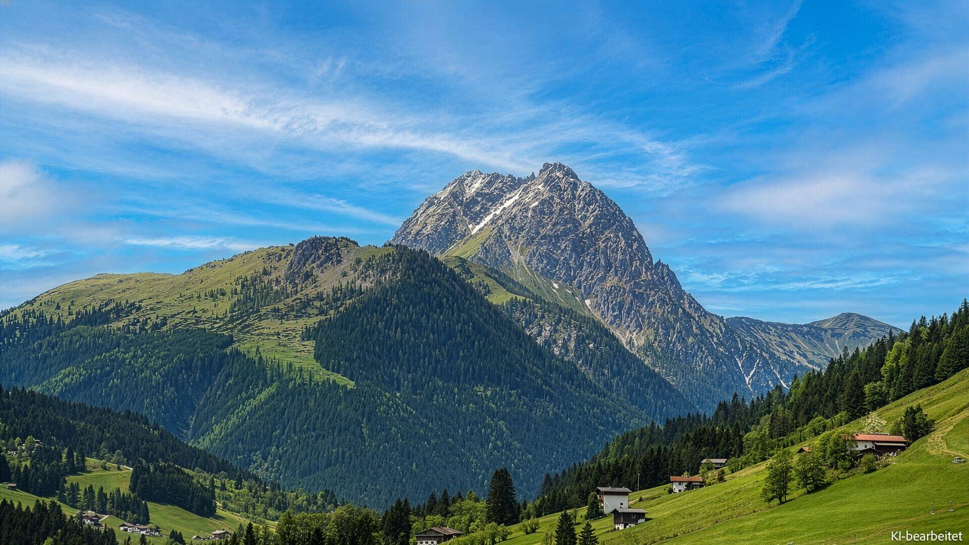 Beeindruckende Nahaufnahme eines schneebedeckten Berggipfels umgeben von grünen Wäldern.