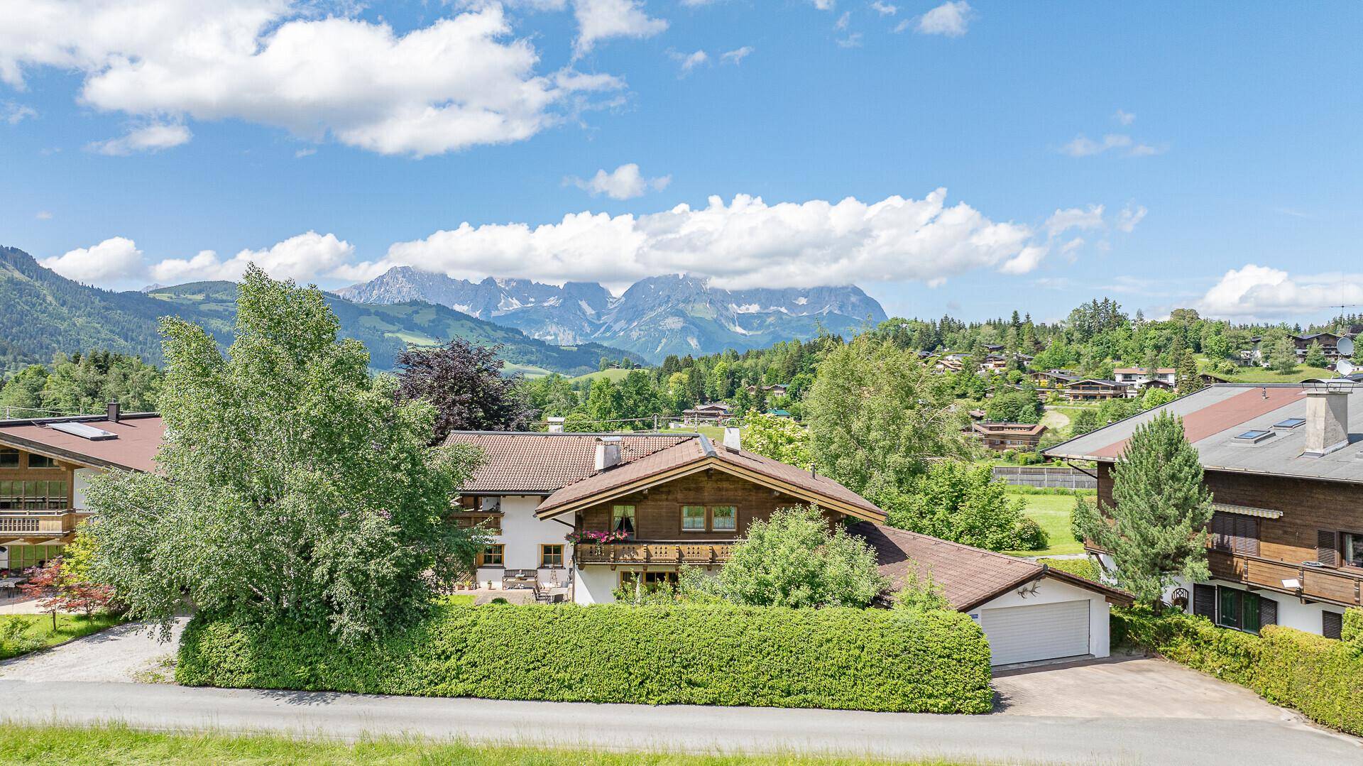Panoramablick auf das Anwesen mit Garage, umgeben von grüner Landschaft und Bergen.