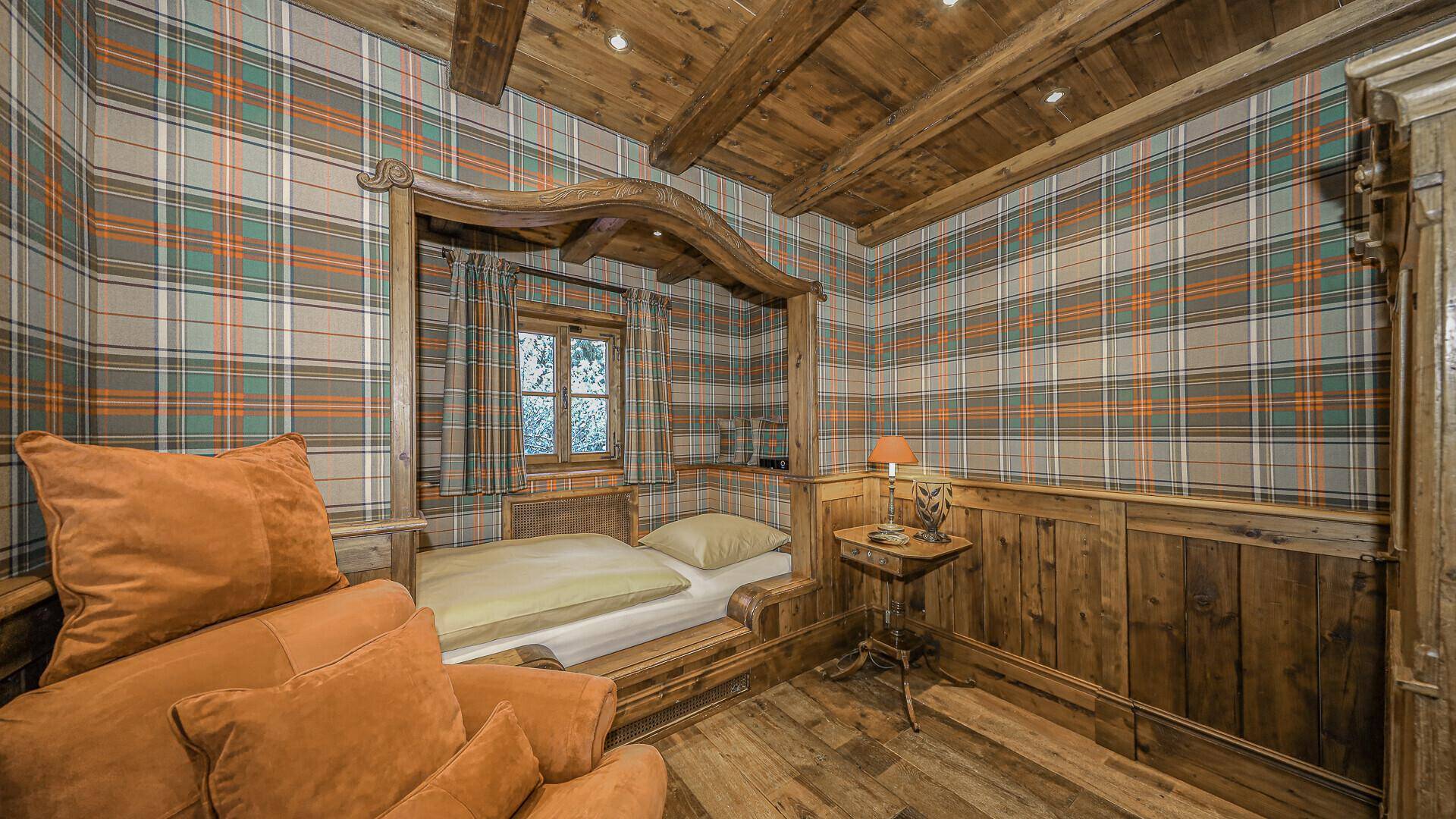 Gemütliches Schlafzimmer mit Holzvertäfelung, karierter Tapete und traditionellem Holzbett.