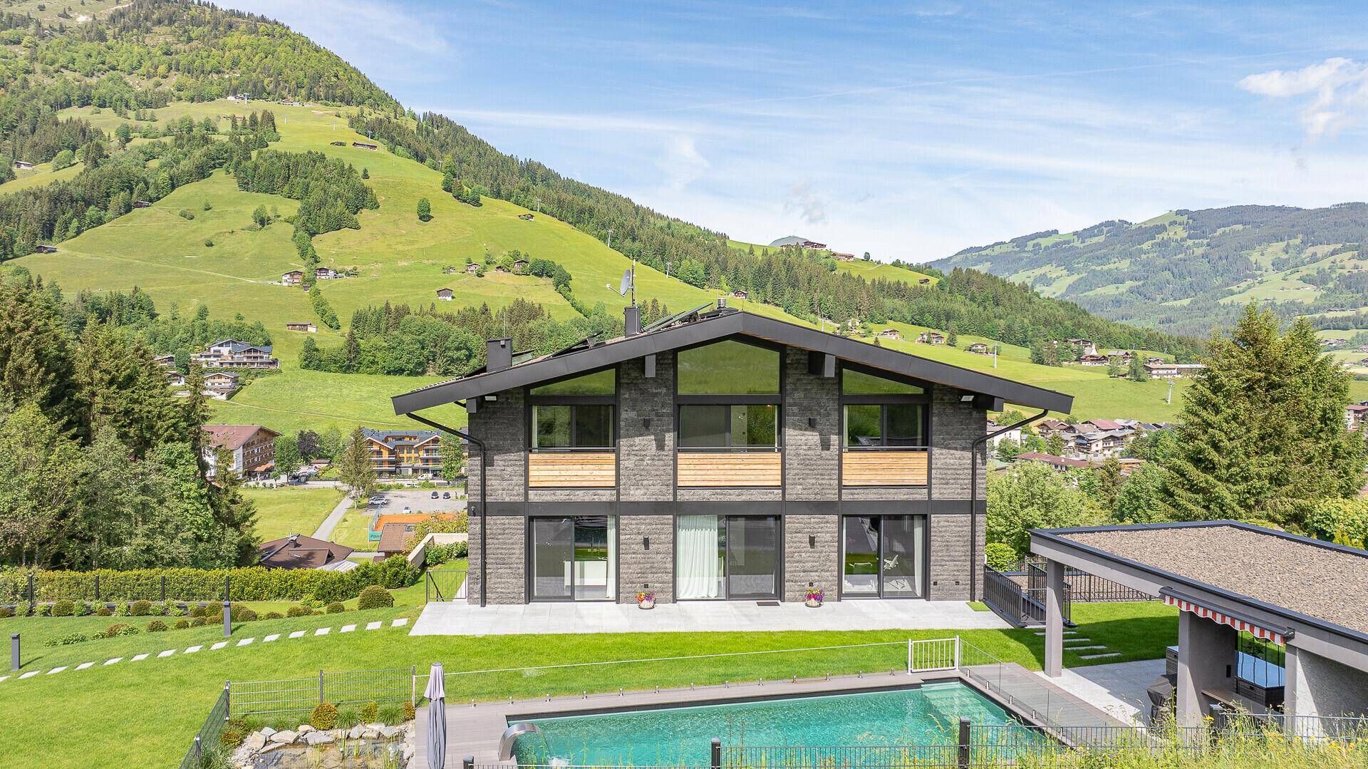 Modernes Haus mit Pool und Garten in einer malerischen Berglandschaft.