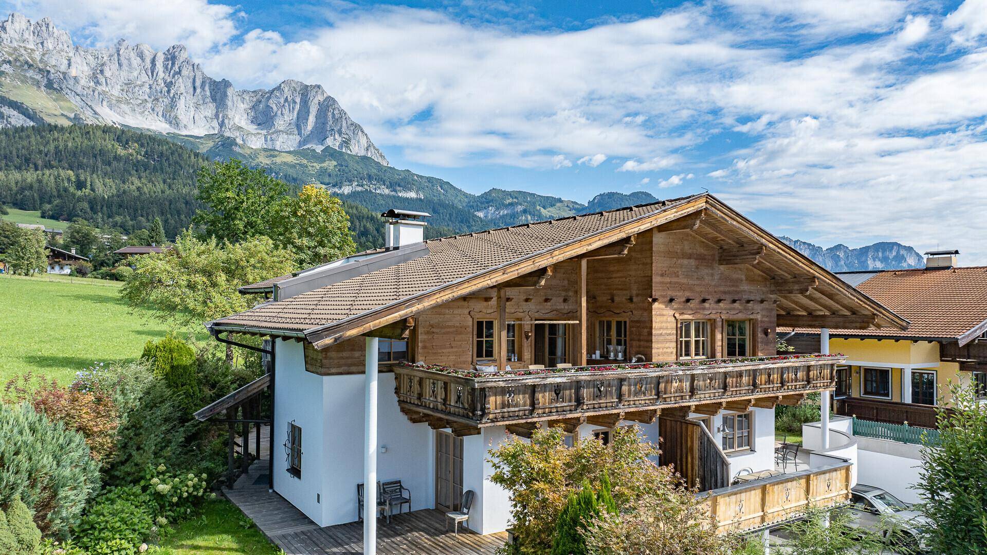 Charmantes Alpenhaus mit Holzbalkonen und traditioneller Architektur vor Bergkulisse.