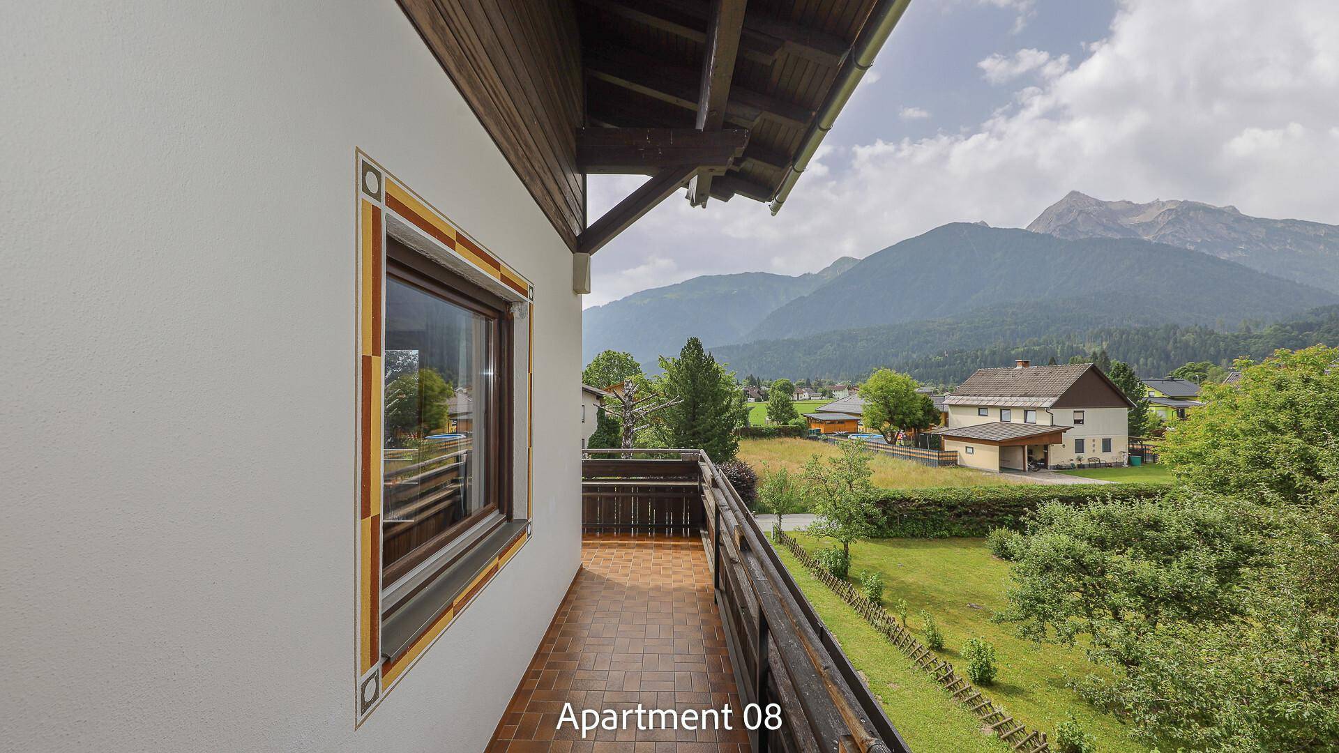 Balkon von Apartment 08 mit Fliesenboden und Holzgeländer, bietet einen weiten Blick auf die Berglandschaft.