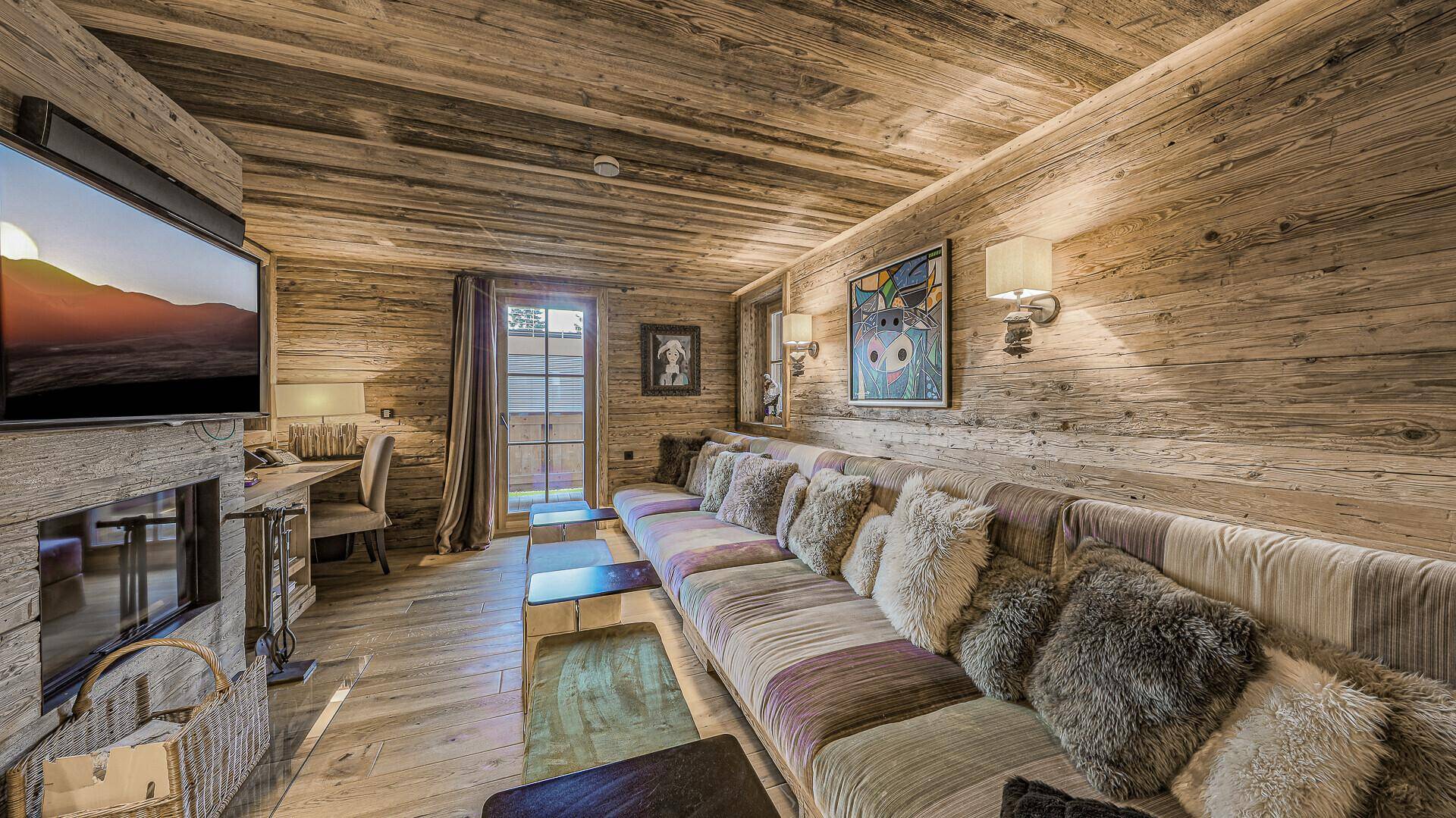 Gemütlicher Wohnbereich mit Holzwänden, langem Sofa und Zugang zu einem kleinen Balkon.