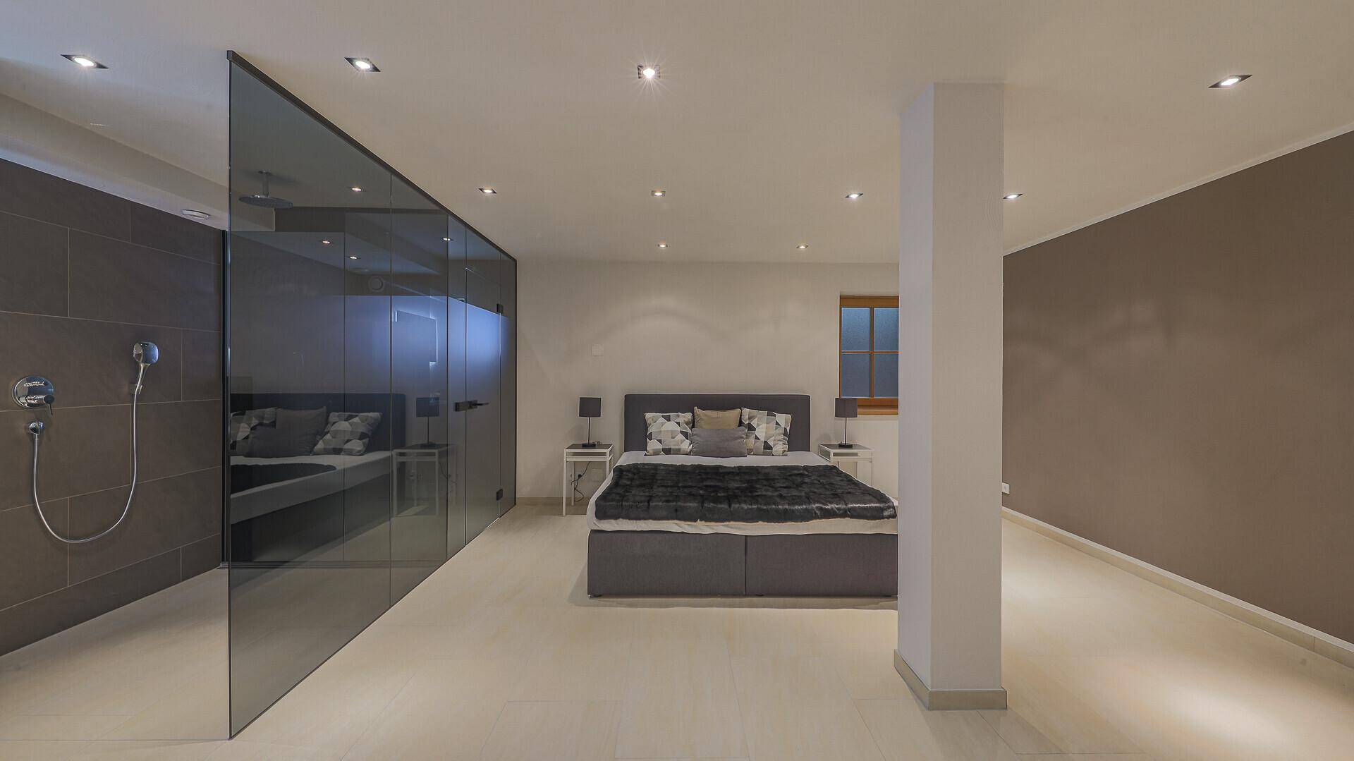 Geräumiges Schlafzimmer mit integriertem Duschbereich und moderner Einrichtung.