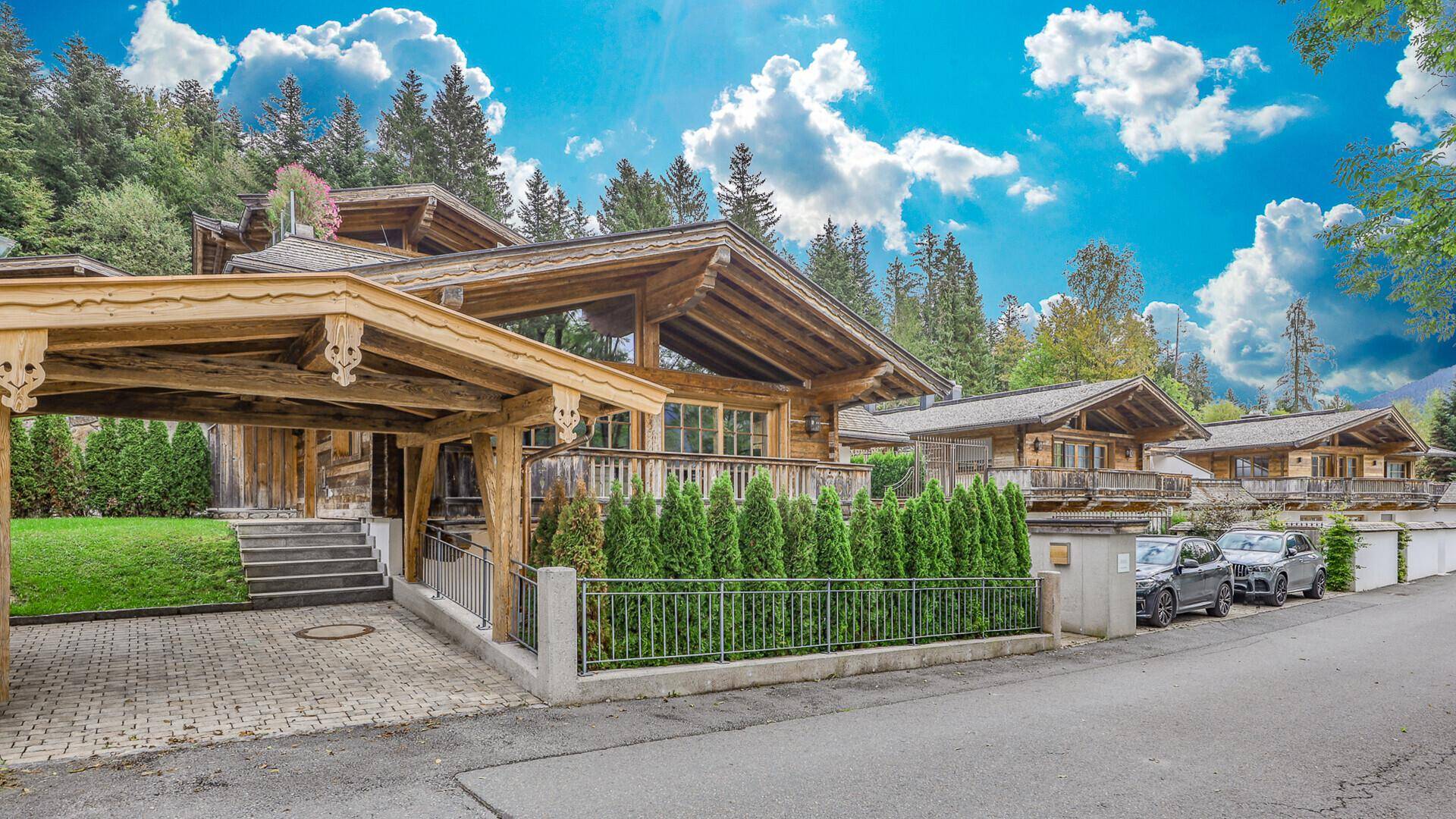 Reihe von charmanten Holzchalets entlang einer Straße mit geparkten Autos und Bergblick.