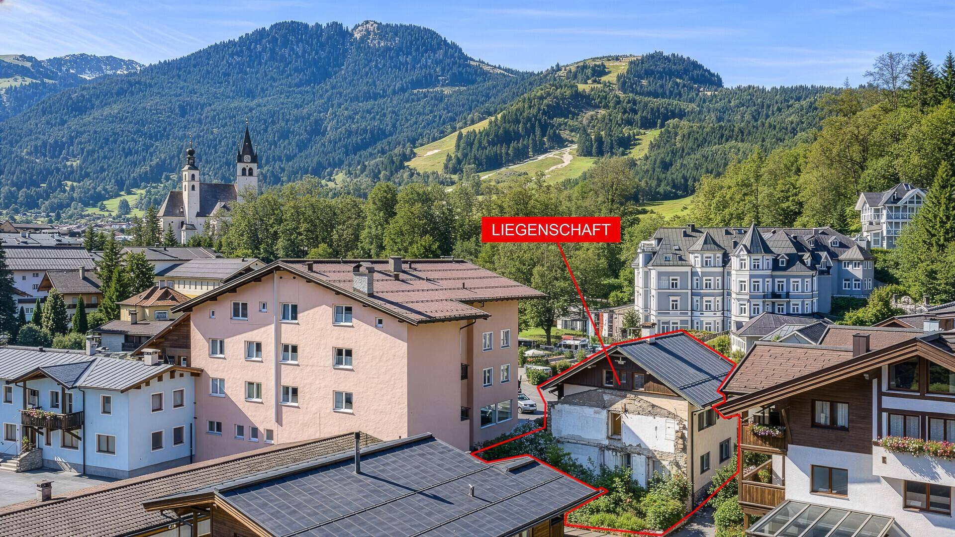 Luftaufnahme des Grundstücks mit umliegenden Gebäuden und der Kirche im Hintergrund, markiert als Liegenschaft.