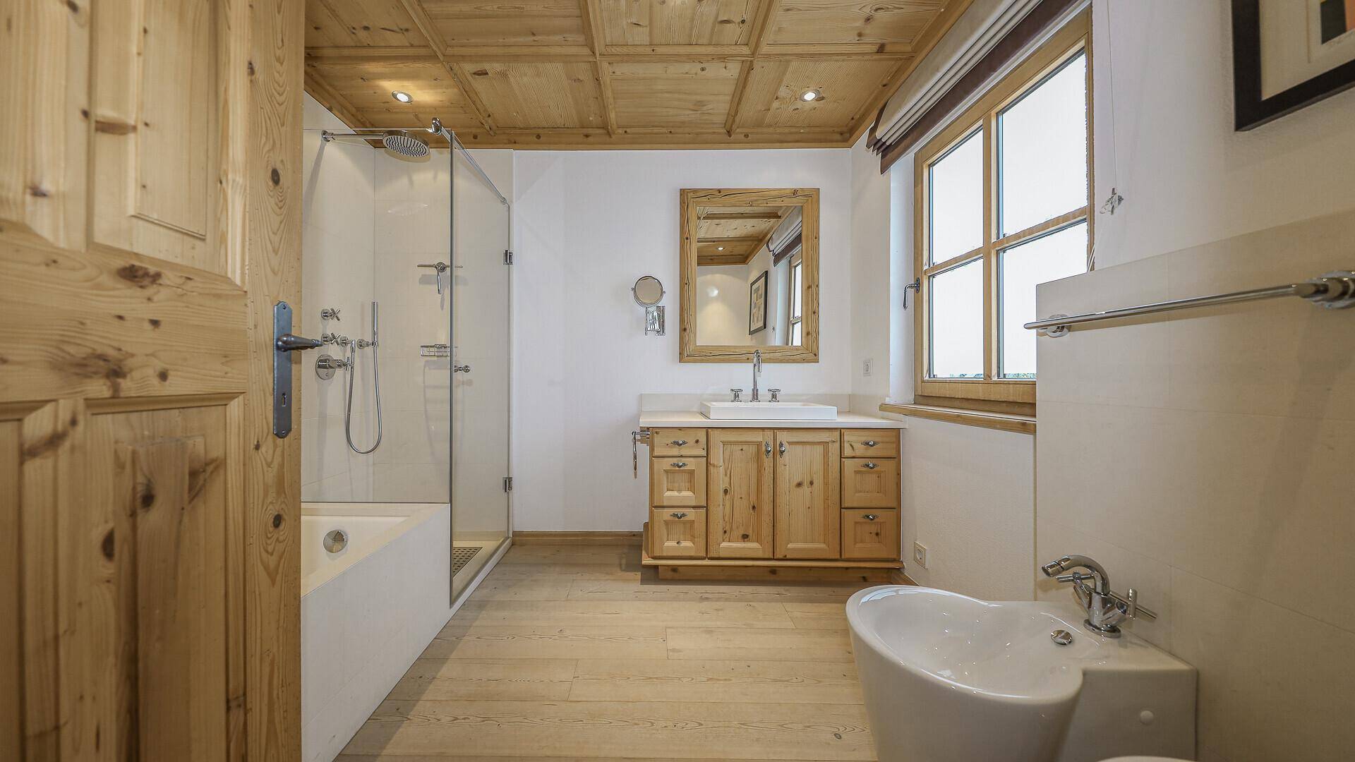 Badezimmer mit Dusche, Bidet und Holzwaschtisch, im alpinen Stil gestaltet.