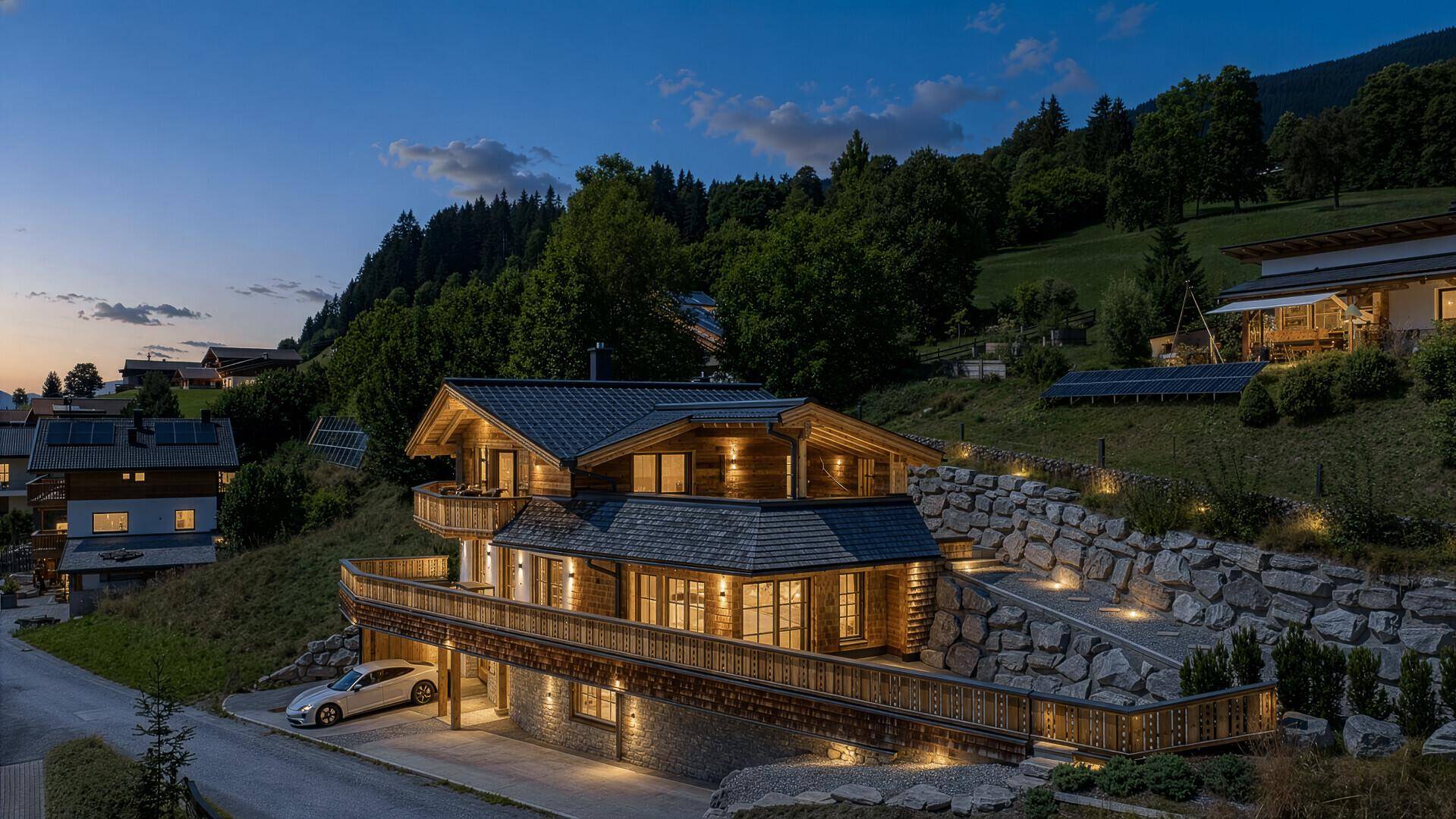Alpines Chalet bei Sonnenuntergang, beleuchtet und eingebettet in die Berglandschaft.