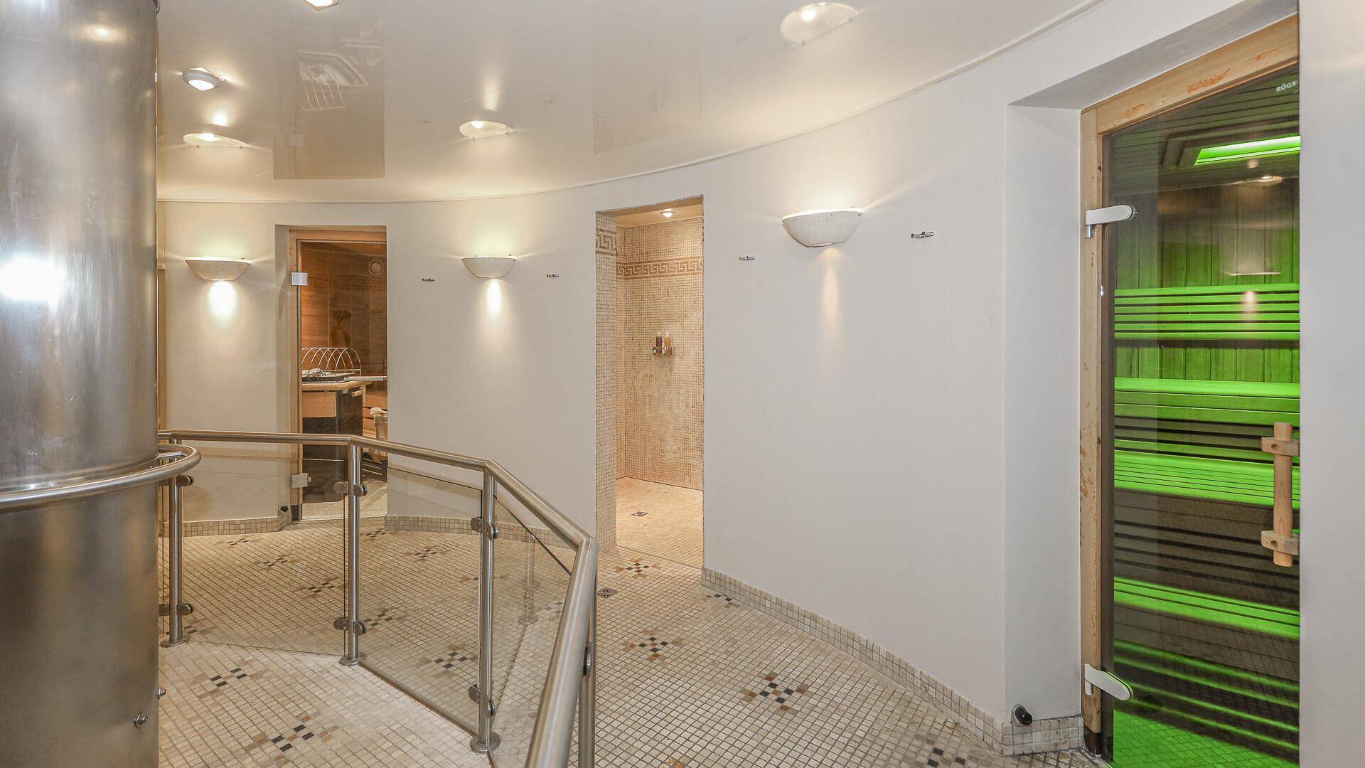 Moderner Wellnessbereich mit Zugang zu Sauna und Dampfbad, elegant gefliest.