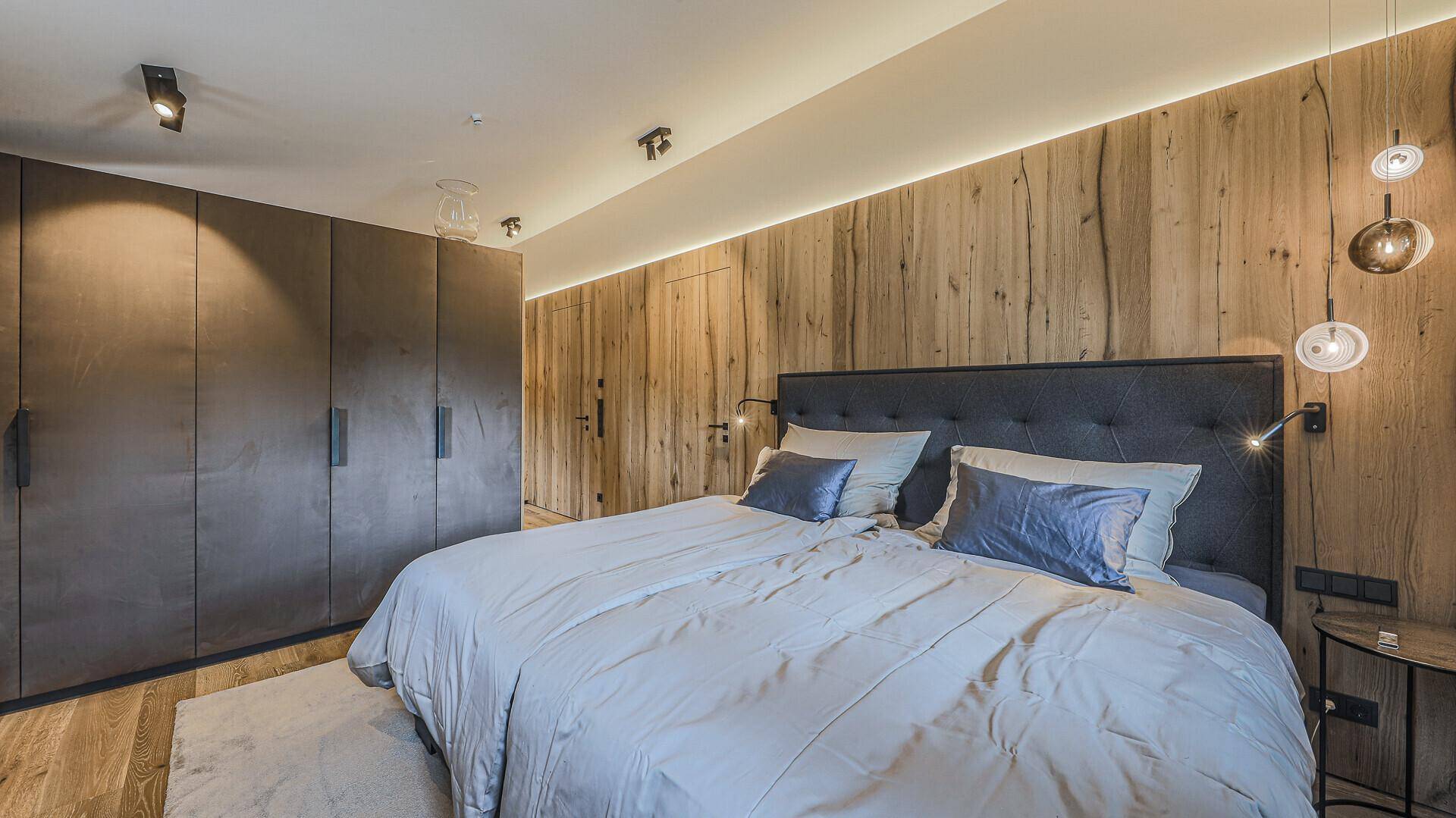 Modernes Schlafzimmer mit Holzwand, Einbauschränken und stilvoller Beleuchtung.