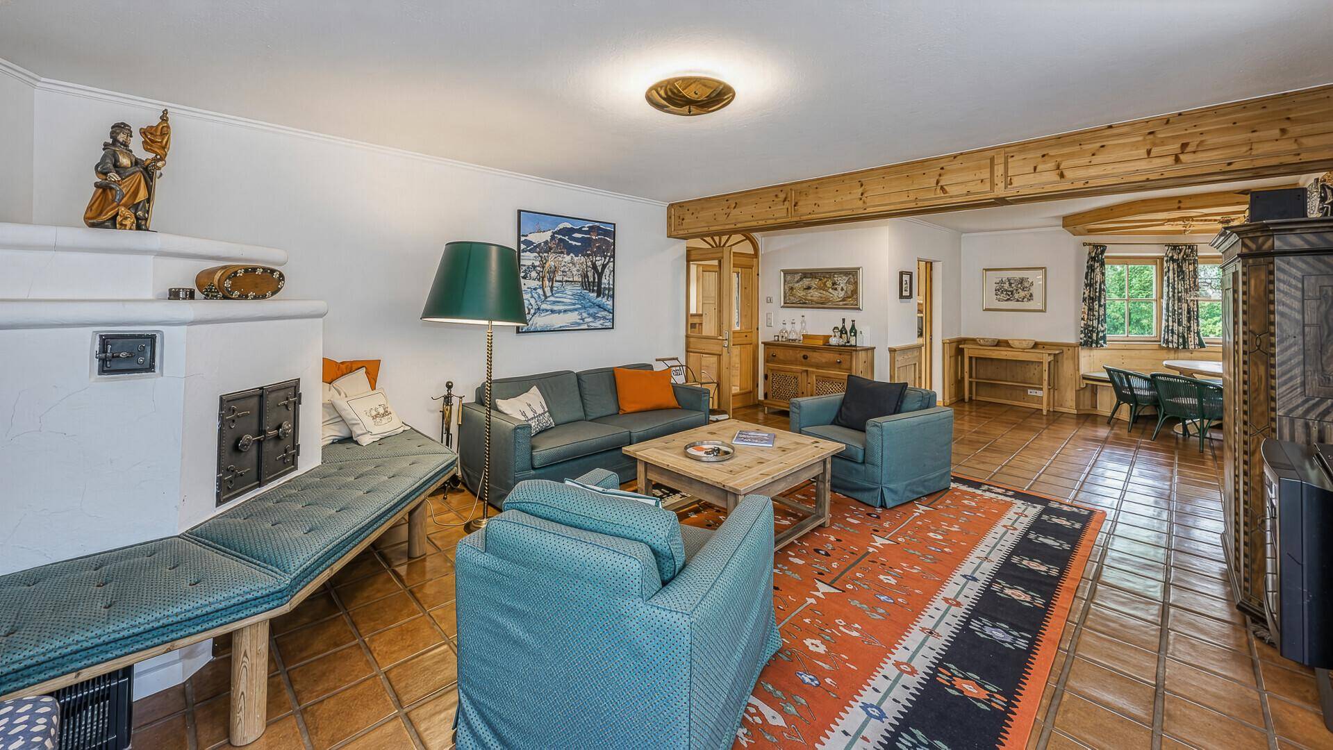 Traditionelles Wohnzimmer mit Kachelofen, rustikalen Möbeln und Essbereich, ideal für gemütliche Abende.