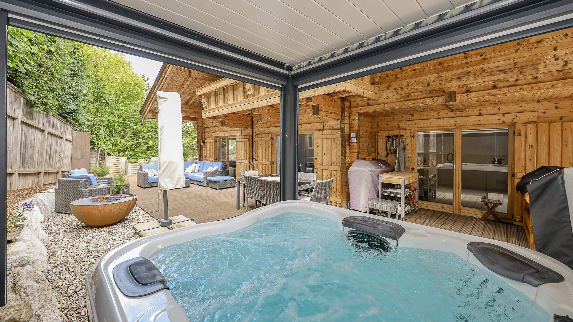 Überdachte Terrasse mit Whirlpool, Essbereich und Zugang zur Küche.