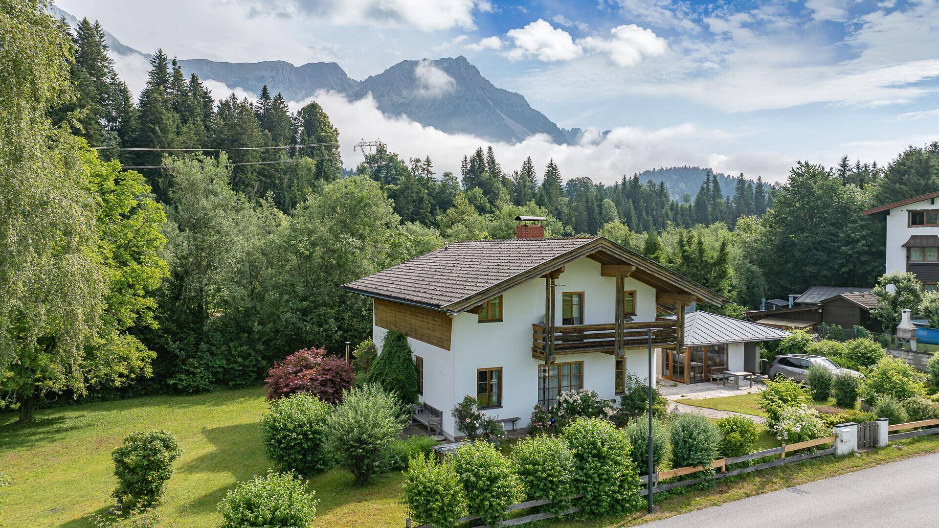 Idyllisches Haus mit traditioneller Architektur und Holzelementen, umgeben von einem großen Garten und Bergpanorama.