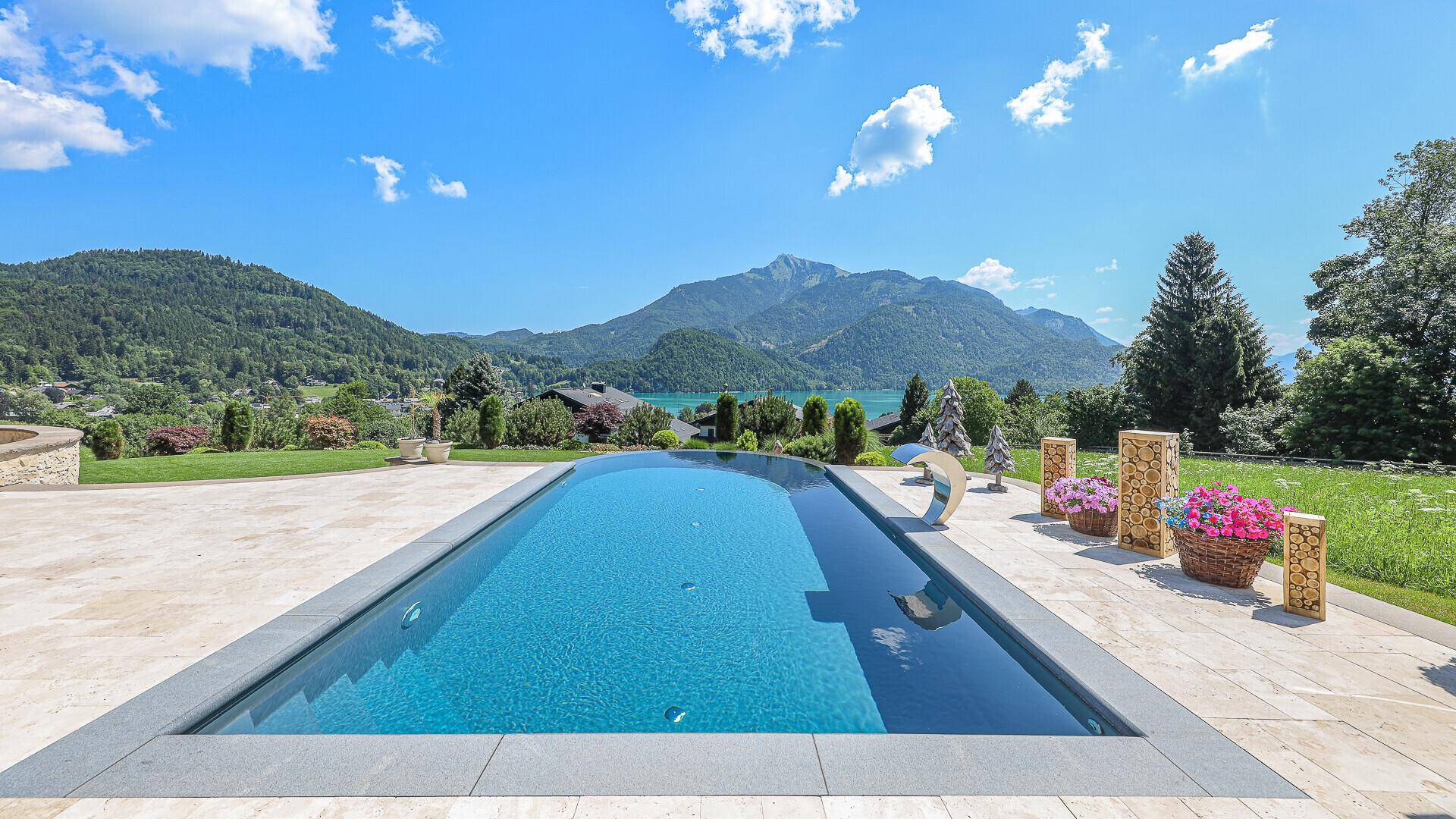Infinity-Pool mit atemberaubendem Blick auf den See und die umliegende Berglandschaft.