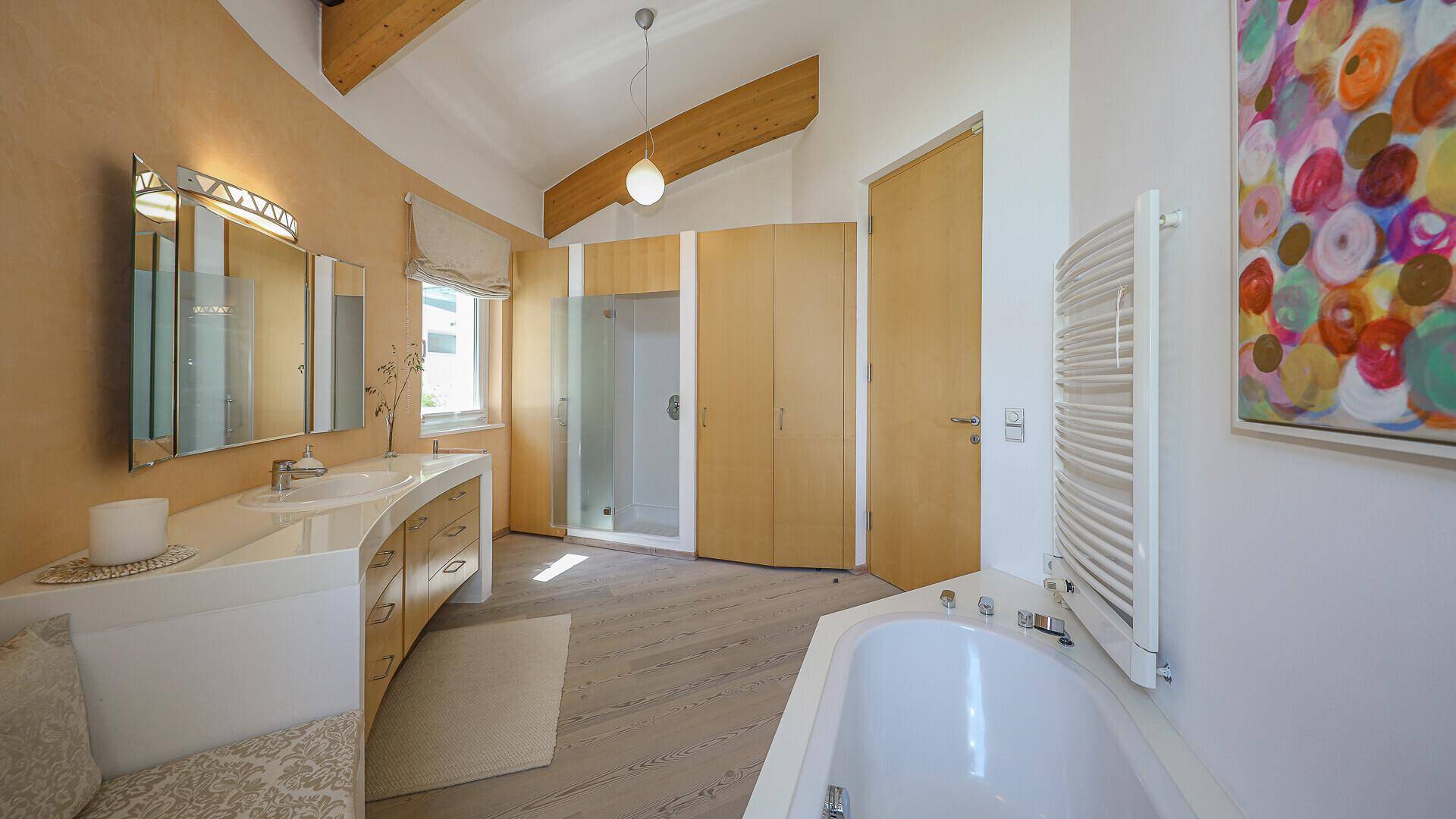 Modernes Badezimmer mit Badewanne, Dusche, Doppelwaschbecken und Holzbalken an der Decke.