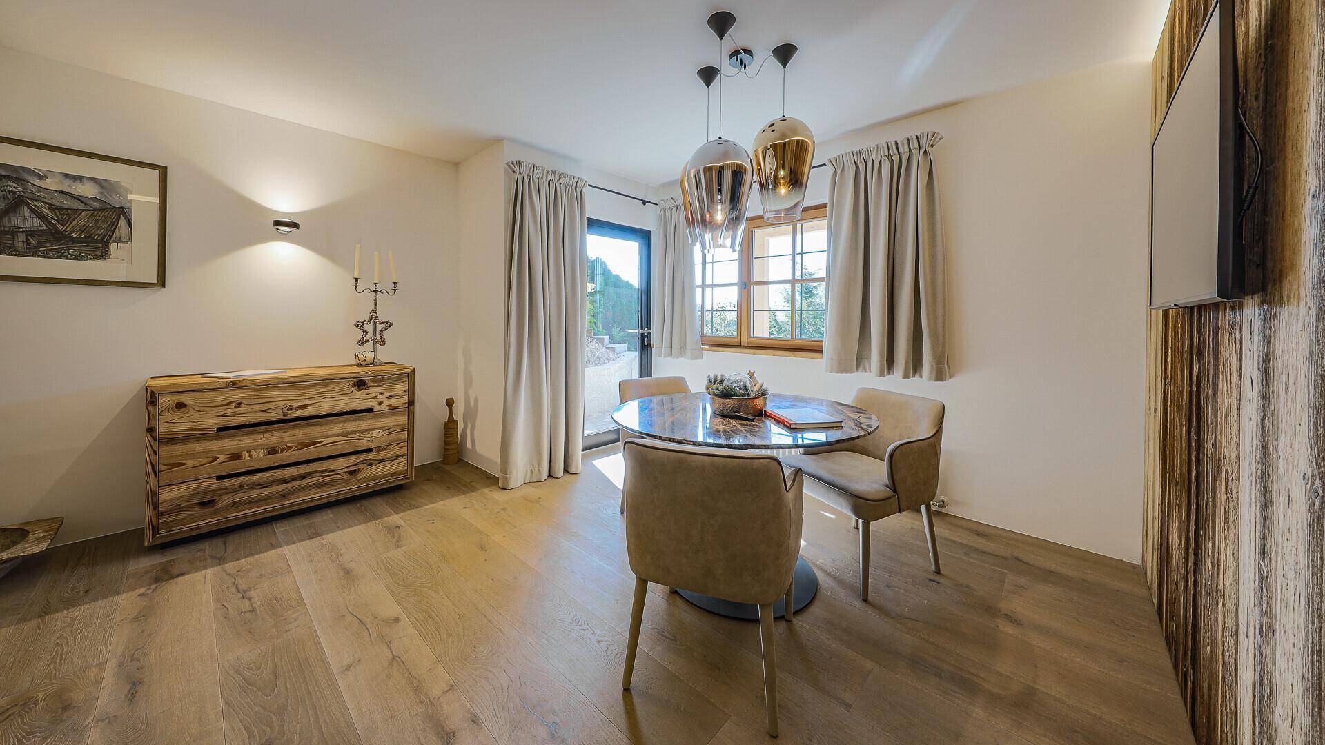 Heller Essbereich mit Holzboden, modernem Tisch und Zugang zu einem Außenbereich.