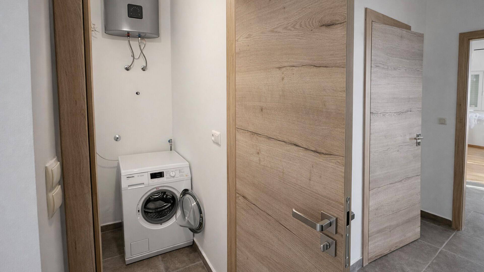 Praktischer Hauswirtschaftsraum mit Waschmaschine und Warmwasserbereiter, ideal für den Alltag.