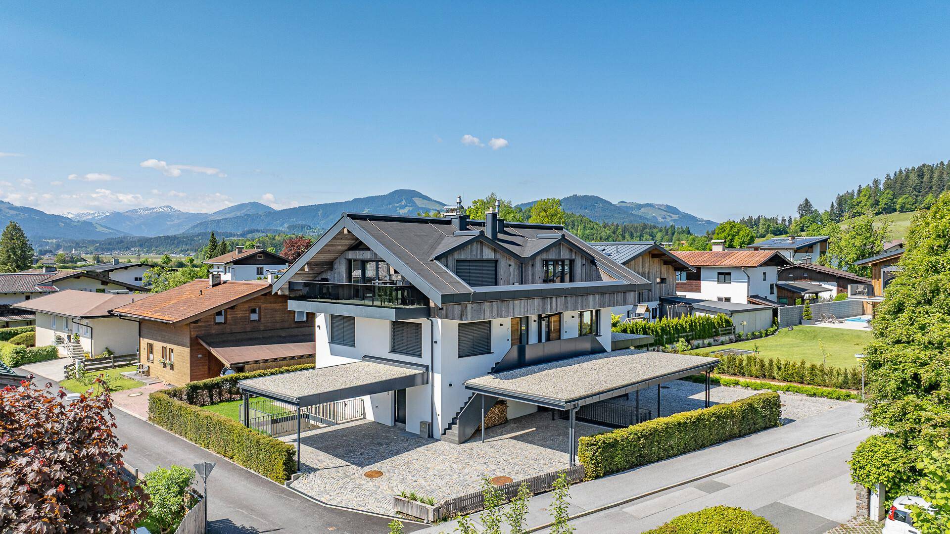 Attraktives Haus mit Bergblick, zwei Carports und gepflasterter Auffahrt.