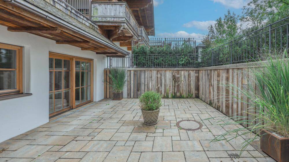 Gepflasterte Terrasse mit Holzzaun und dekorativen Pflanzen in Töpfen.