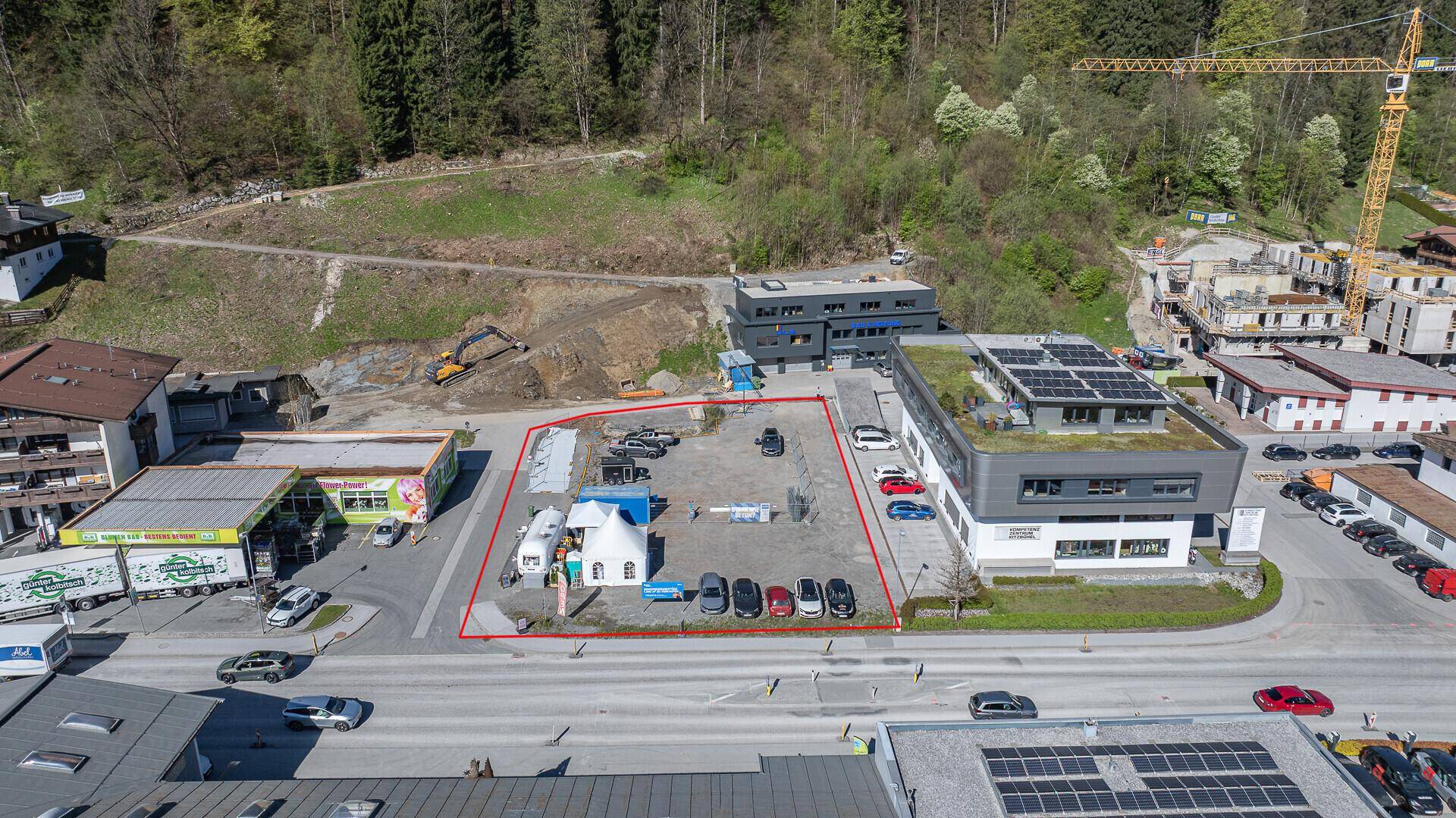Luftaufnahme des rot umrandeten Grundstücks mit Parkplätzen und modernen Nachbargebäuden.