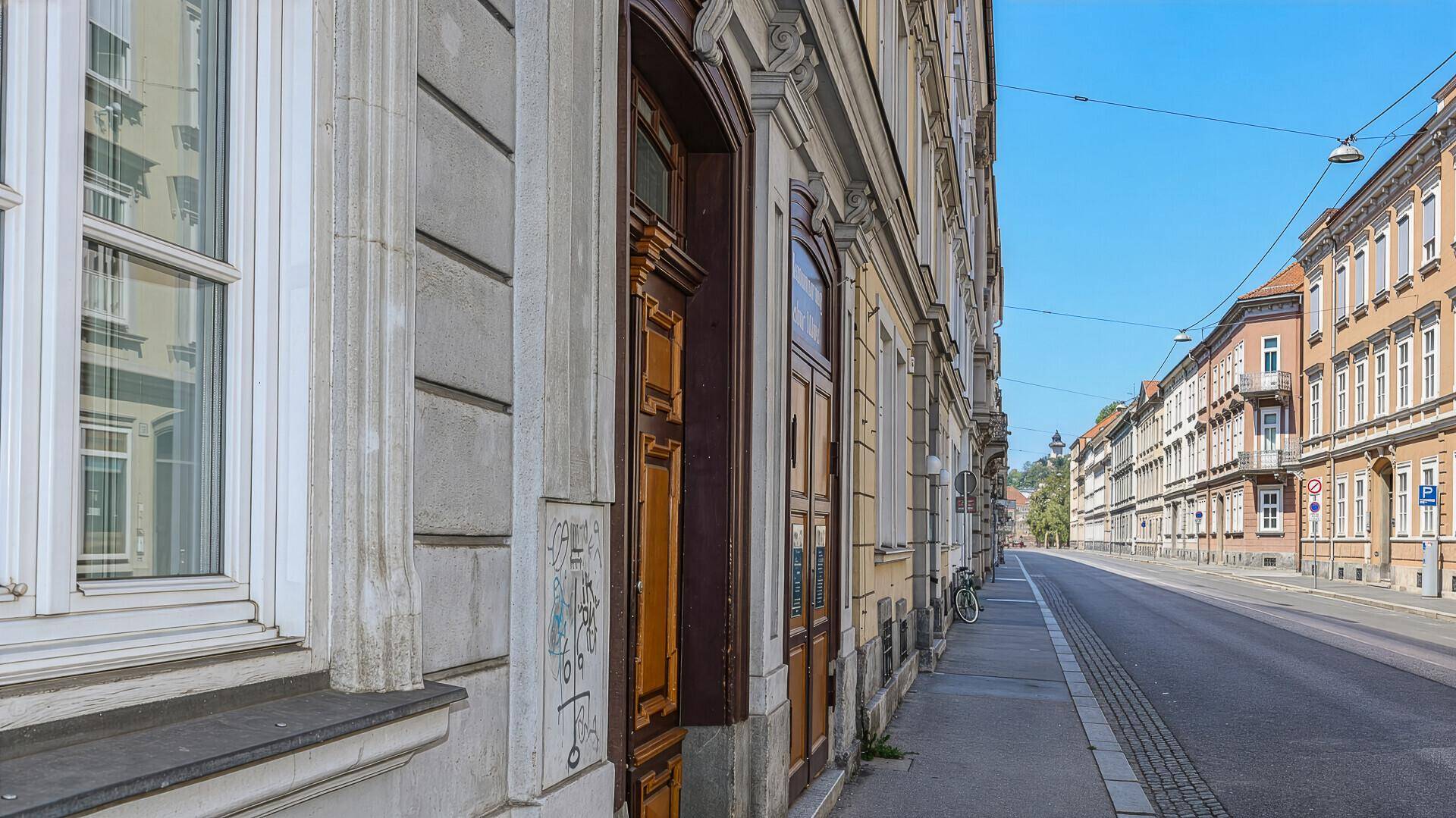 Nahaufnahme der Gebäudefassade mit verzierten Türen und Fenstern entlang der Straße.