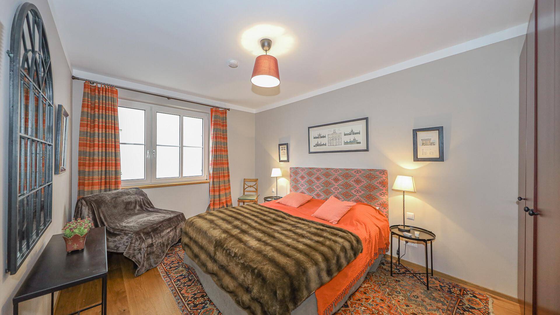 Gemütliches Schlafzimmer mit Doppelbett, Holzboden und farbenfrohen Vorhängen.
