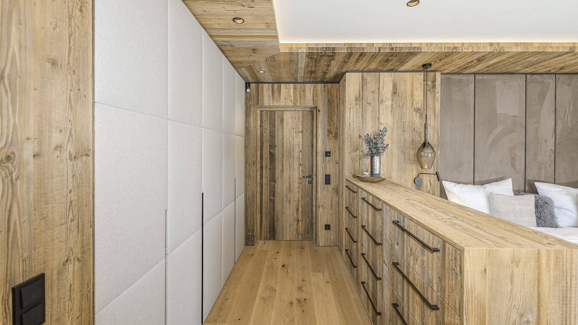 Schlafzimmerbereich mit integrierten Schränken, Holzelementen und viel Stauraum.
