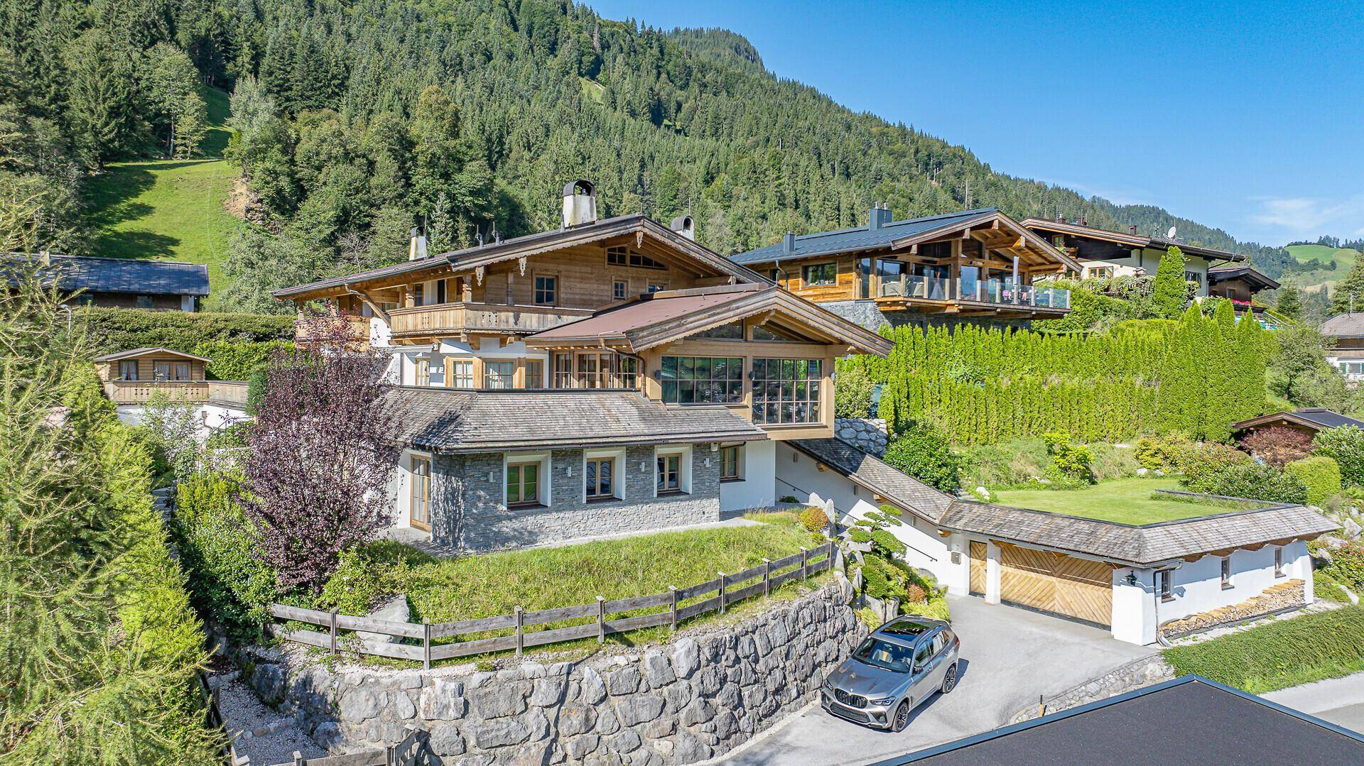 Großzügiges Anwesen in den Bergen mit traditioneller Holz- und Steinfassade und üppiger Vegetation.