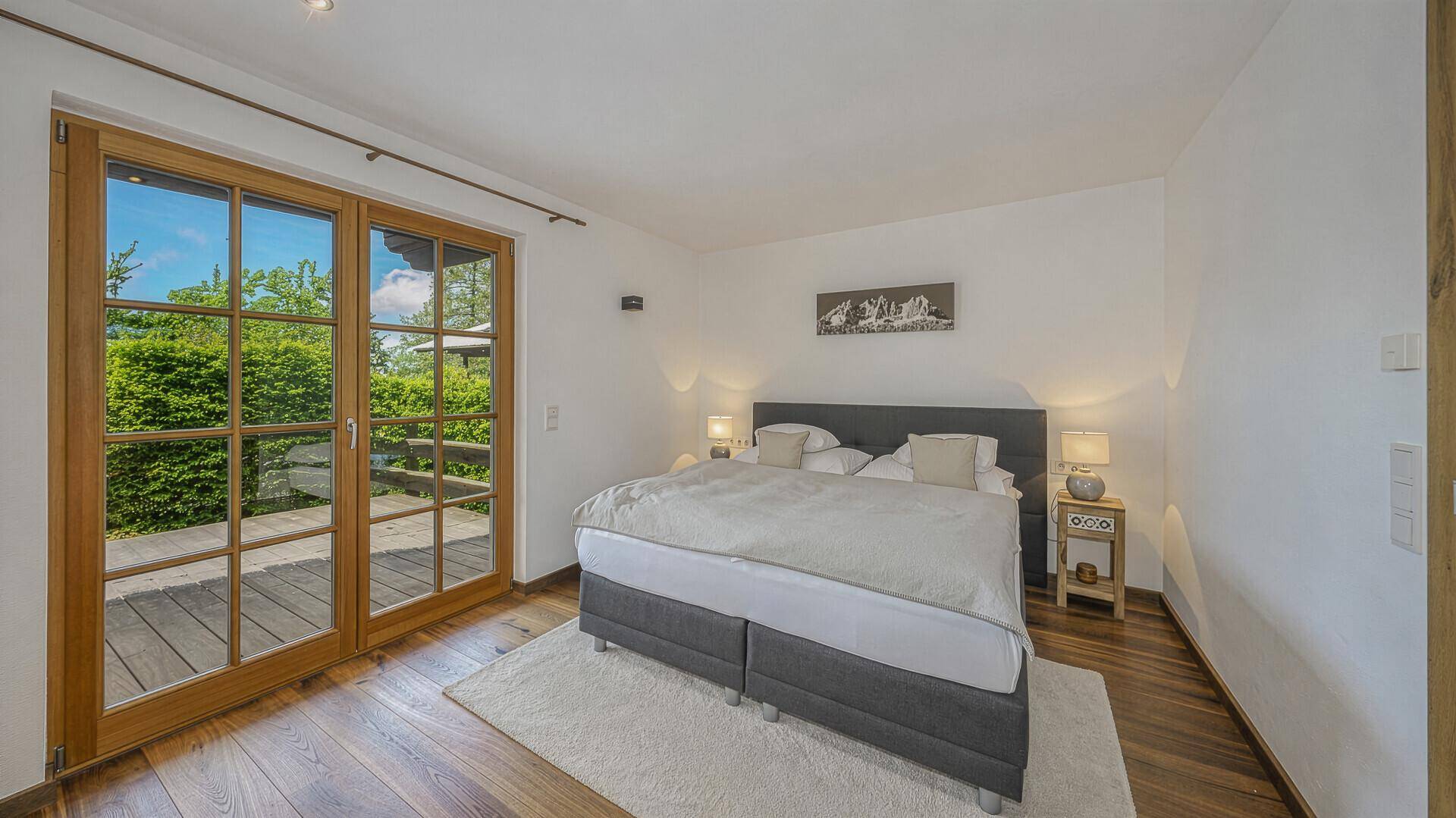 Gemütliches Schlafzimmer mit Doppelbett, Holzboden und Zugang zur Terrasse.