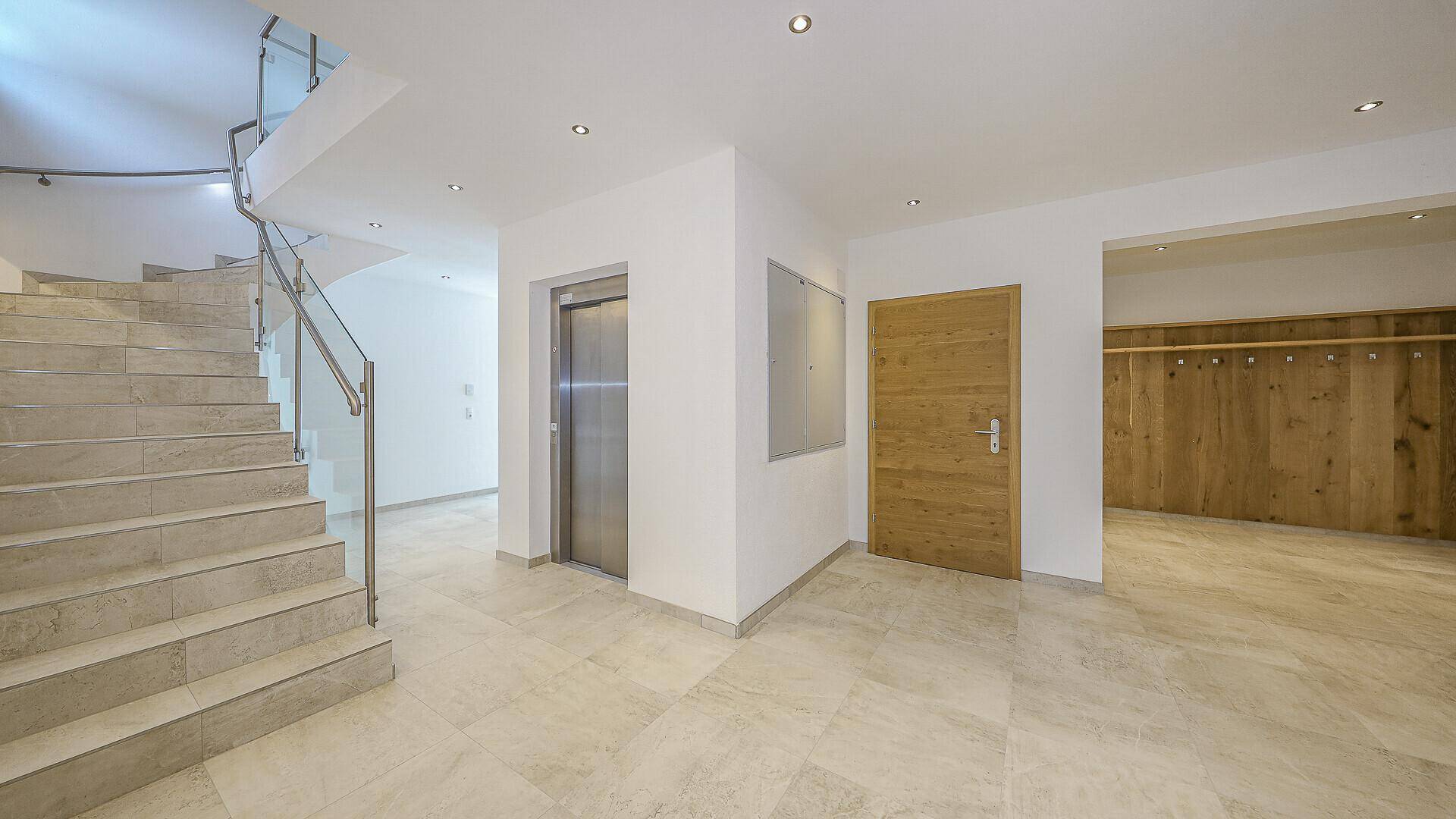 Geräumiger Eingangsbereich mit Aufzug, Treppe und Garderobenbereich.