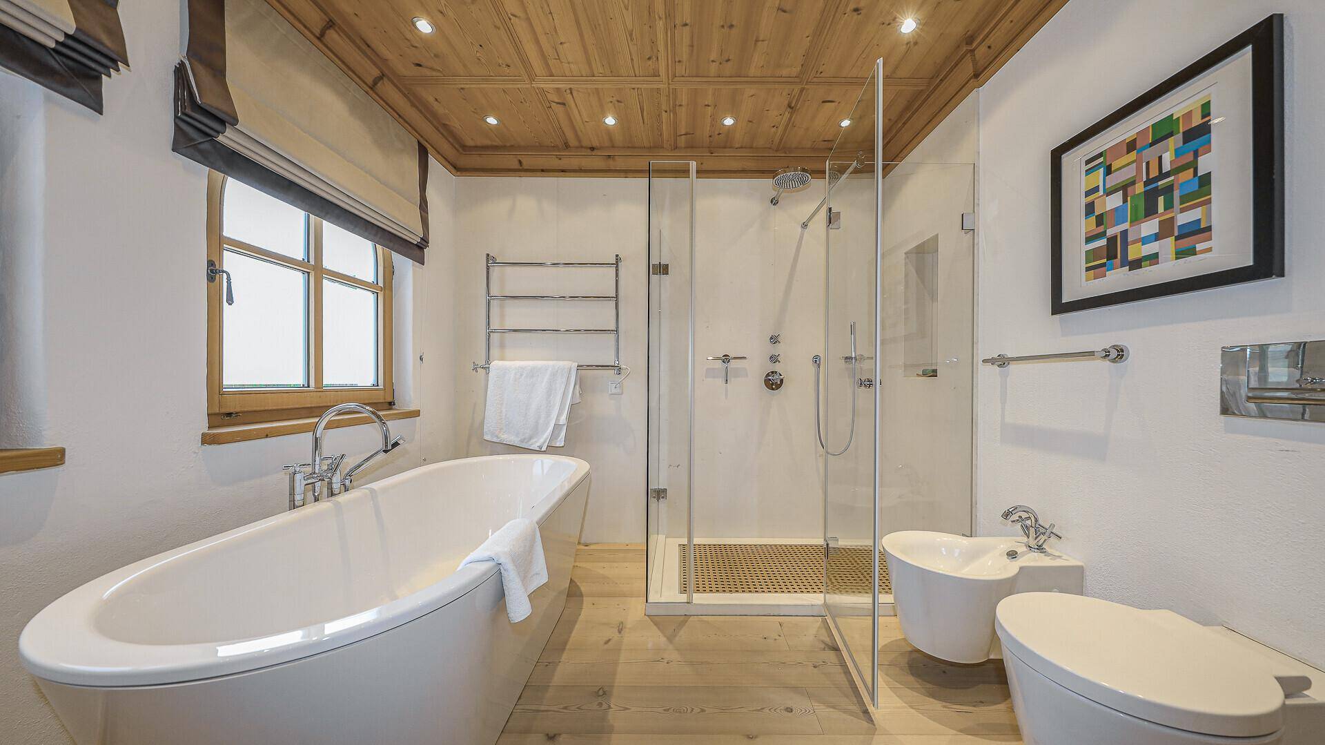 Modernes Badezimmer mit freistehender Badewanne, ebenerdiger Dusche und Holzbalkendecke.