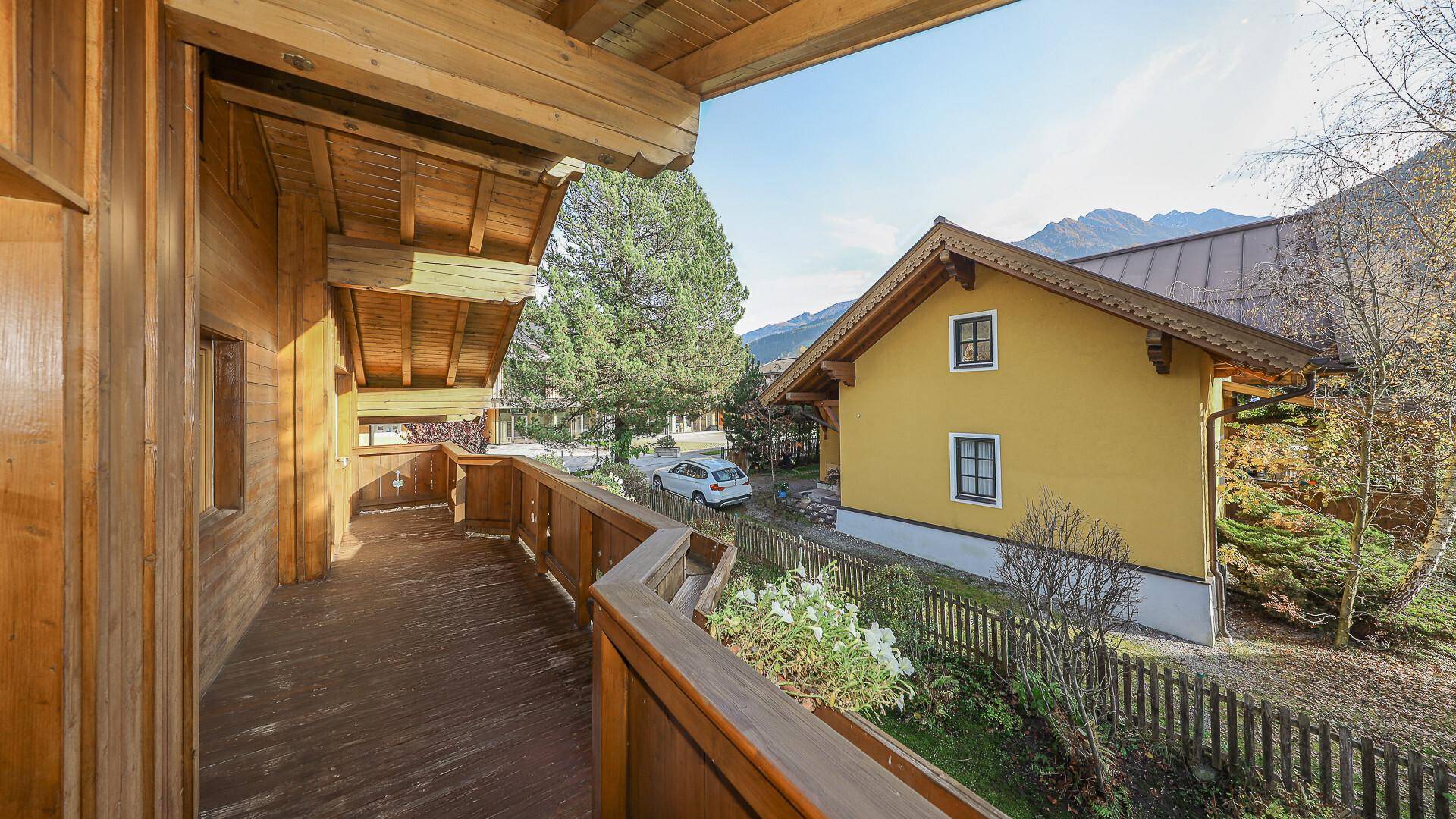 Traditioneller Holzbalkon mit Geländer und Blick auf die umliegende Landschaft.