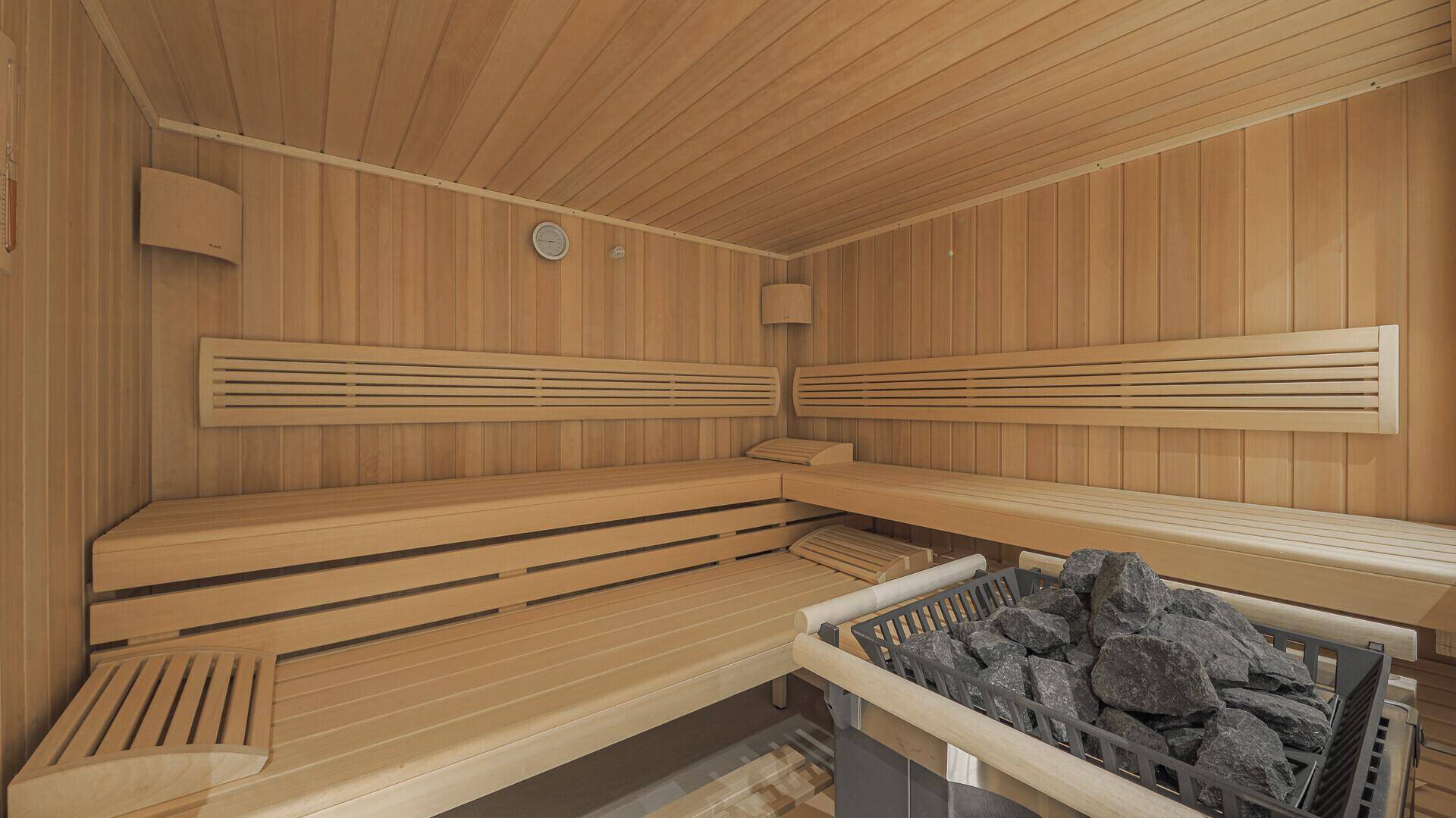 Traditionelle Holzsauna mit mehreren Bänken und einem Saunaofen mit Steinen.