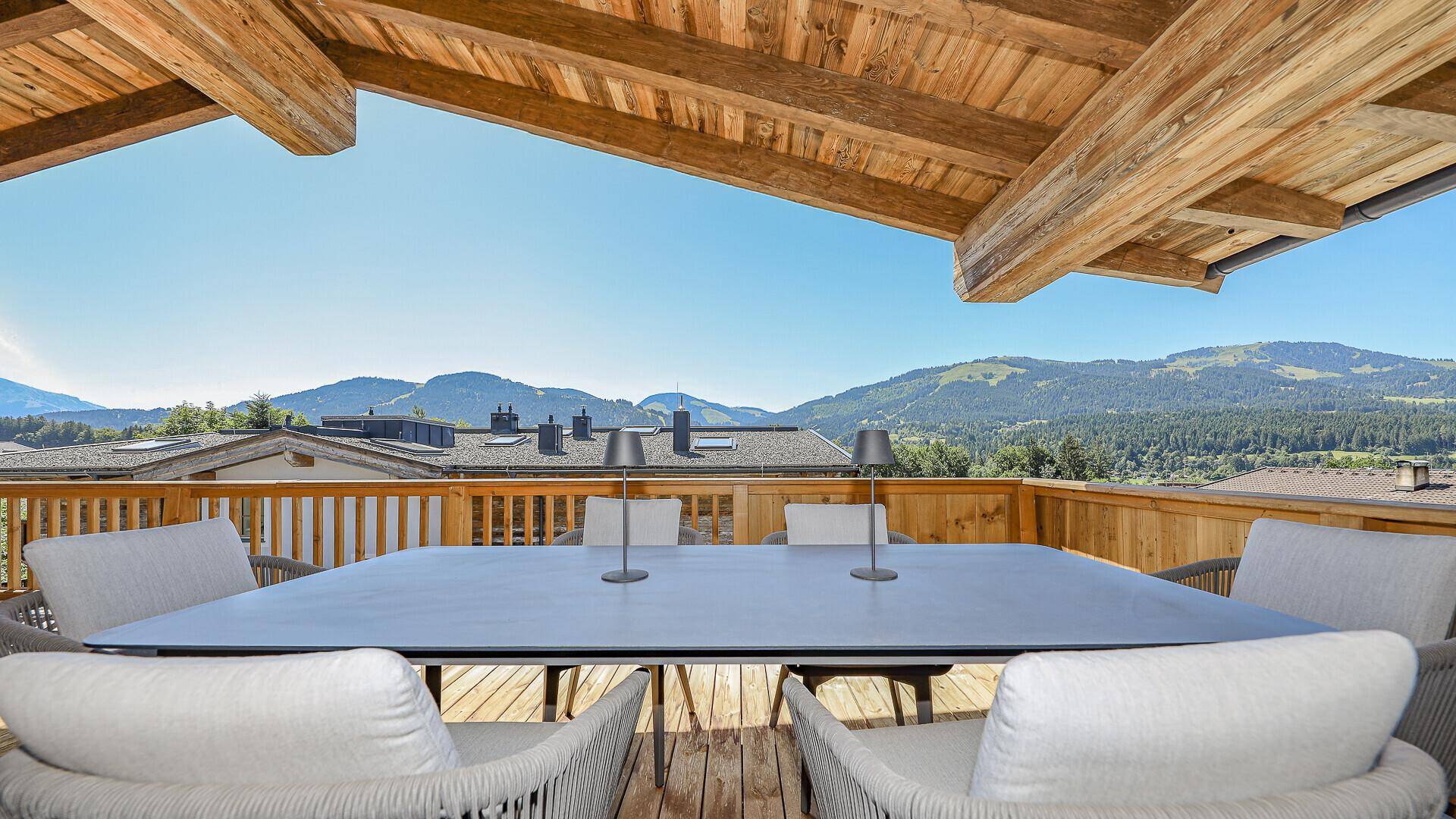 Sonniger Balkon mit Holzboden und Essbereich, ideal für Mahlzeiten mit Bergblick.