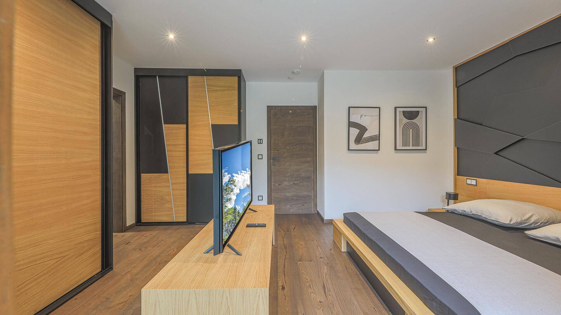 Helles Schlafzimmer mit Holzboden, modernem Kleiderschrank und minimalistischer Einrichtung.