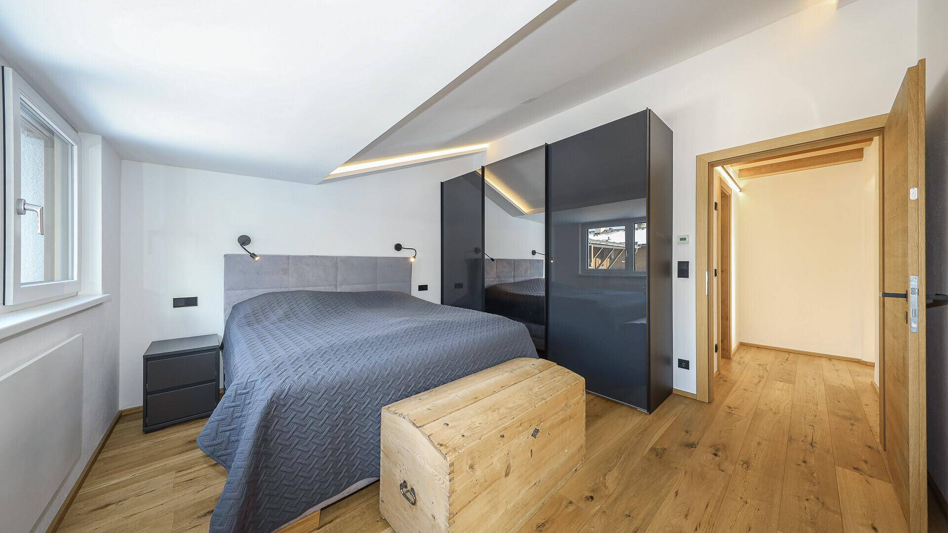 Modernes Schlafzimmer mit Holzboden, Einbauschränken und Zugang zum Flur.