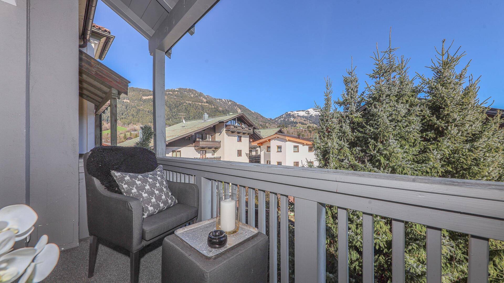 Sonniger Balkon mit bequemen Stühlen und Panoramablick auf die Alpenlandschaft.