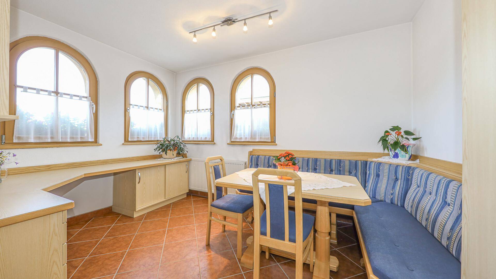 Gemütlicher Essbereich mit Eckbank, Holztisch und Bogenfenstern.