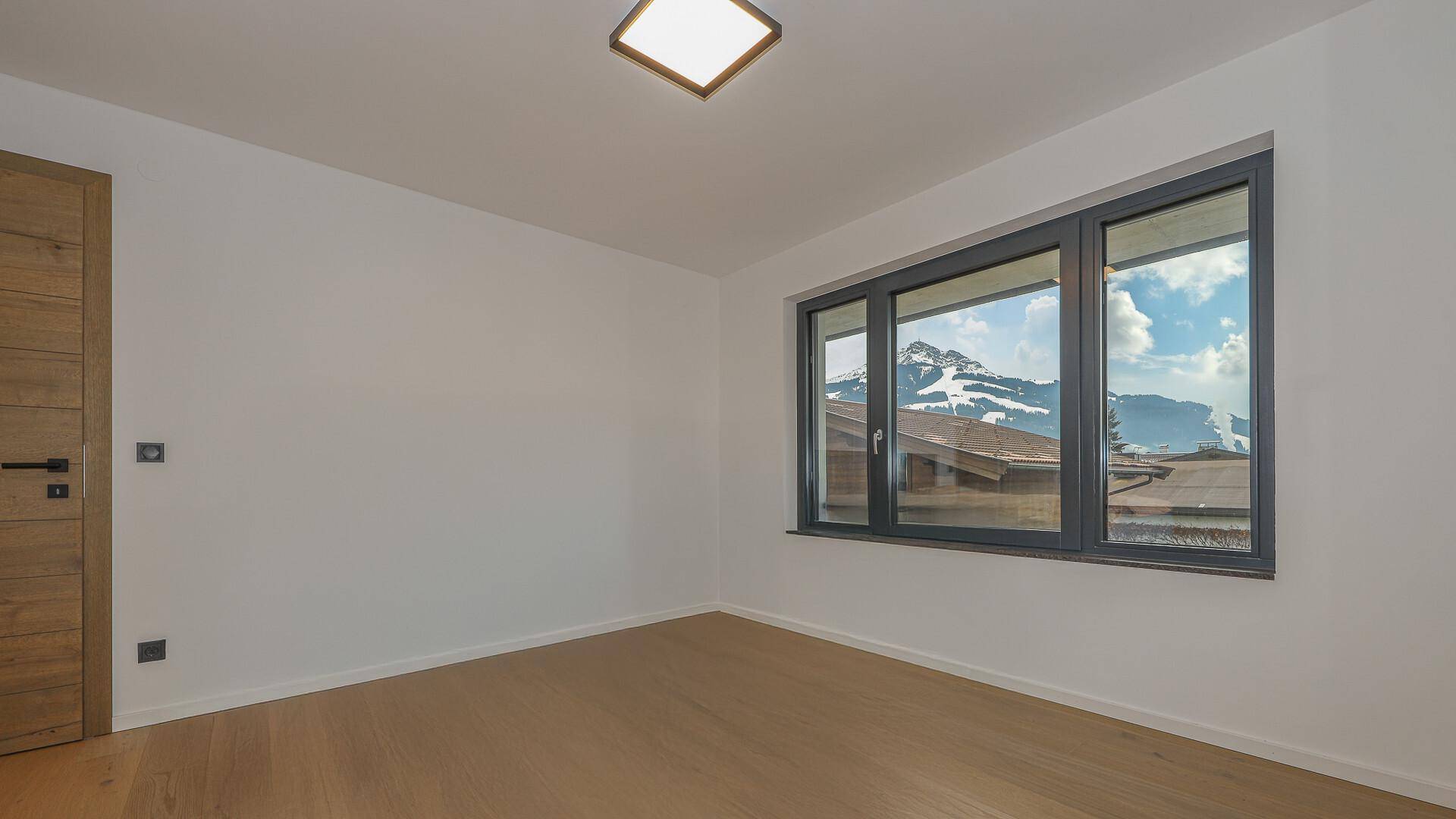 Schlafzimmer mit Holztür und Fenster, das einen schönen Blick auf die Berge freigibt.